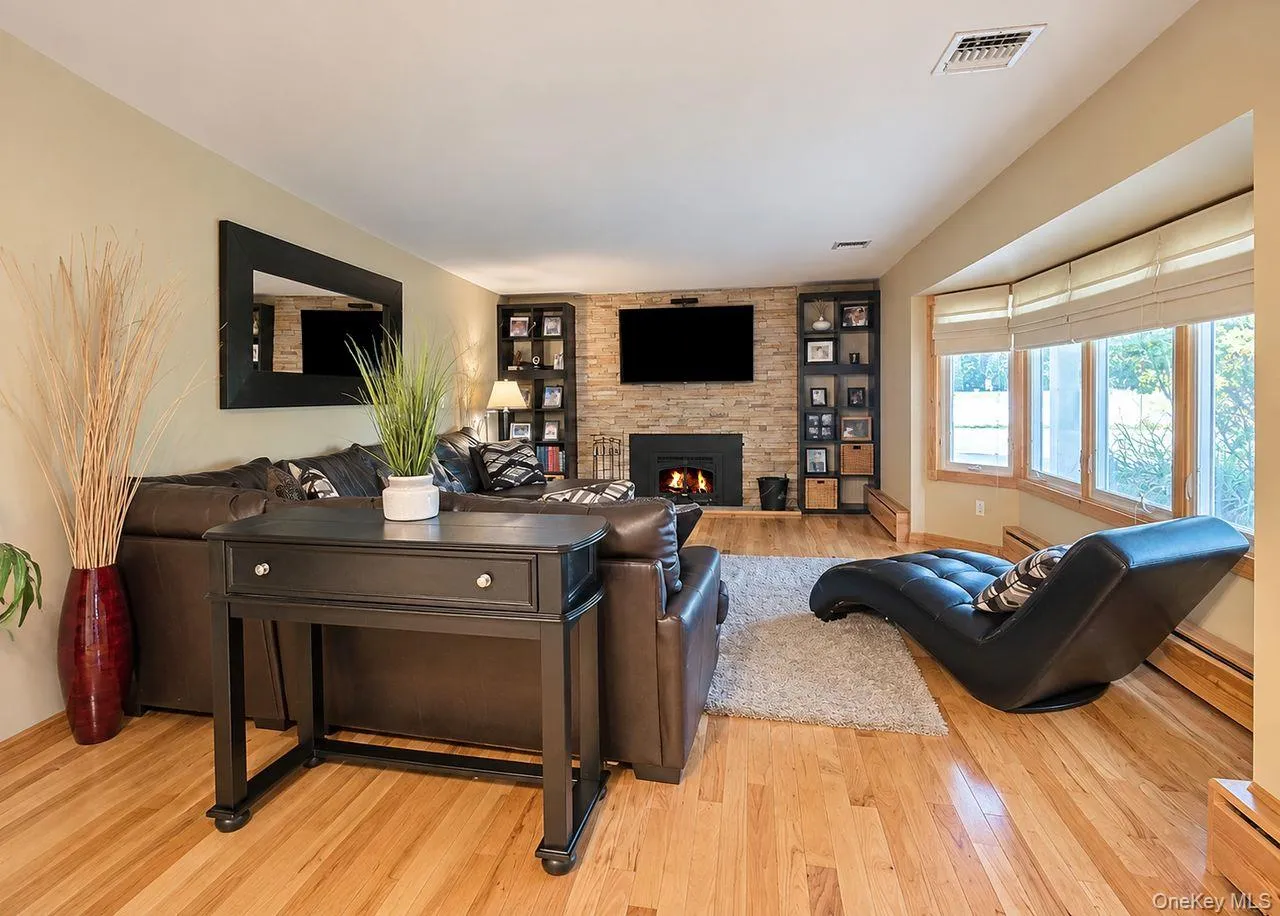 Wood-finish flooring throughout, a stone-clad fireplace, and integrated shelving fireplace with insert Wood-finish flooring throughout, a stone-clad fireplace, and integrated shelving fireplace with insert