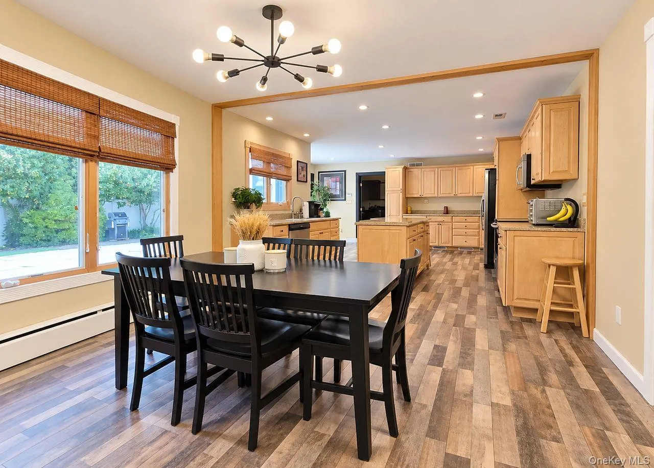 Open-concept dining area with wood-finish flooring, a contemporary chandelier, and large windows Open-concept dining area with wood-finish flooring, a contemporary chandelier, and large windows