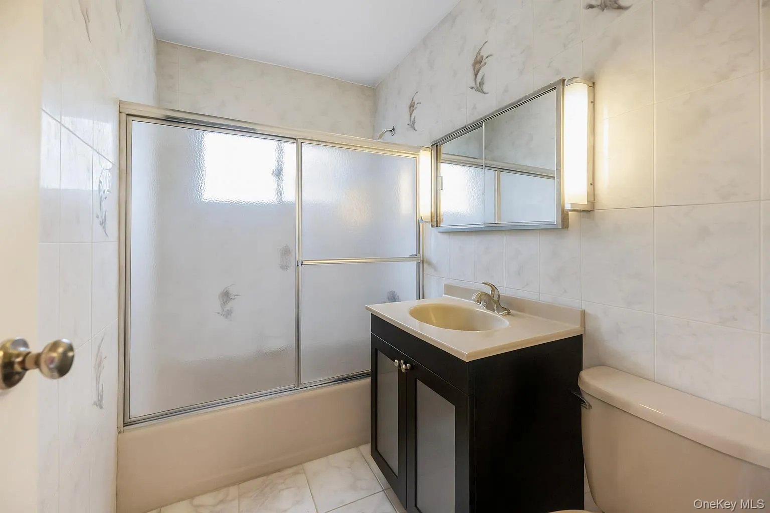 Full bathroom featuring enclosed tub / shower combo, vanity, and tile walls Full bathroom featuring enclosed tub / shower combo, vanity, and tile walls