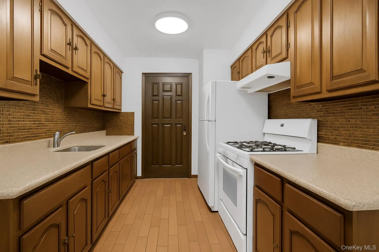 Kitchen with tasteful backsplash, white gas range, under cabinet range hood, and brown cabinets Kitchen with tasteful backsplash, white gas range, under cabinet range hood, and brown cabinets