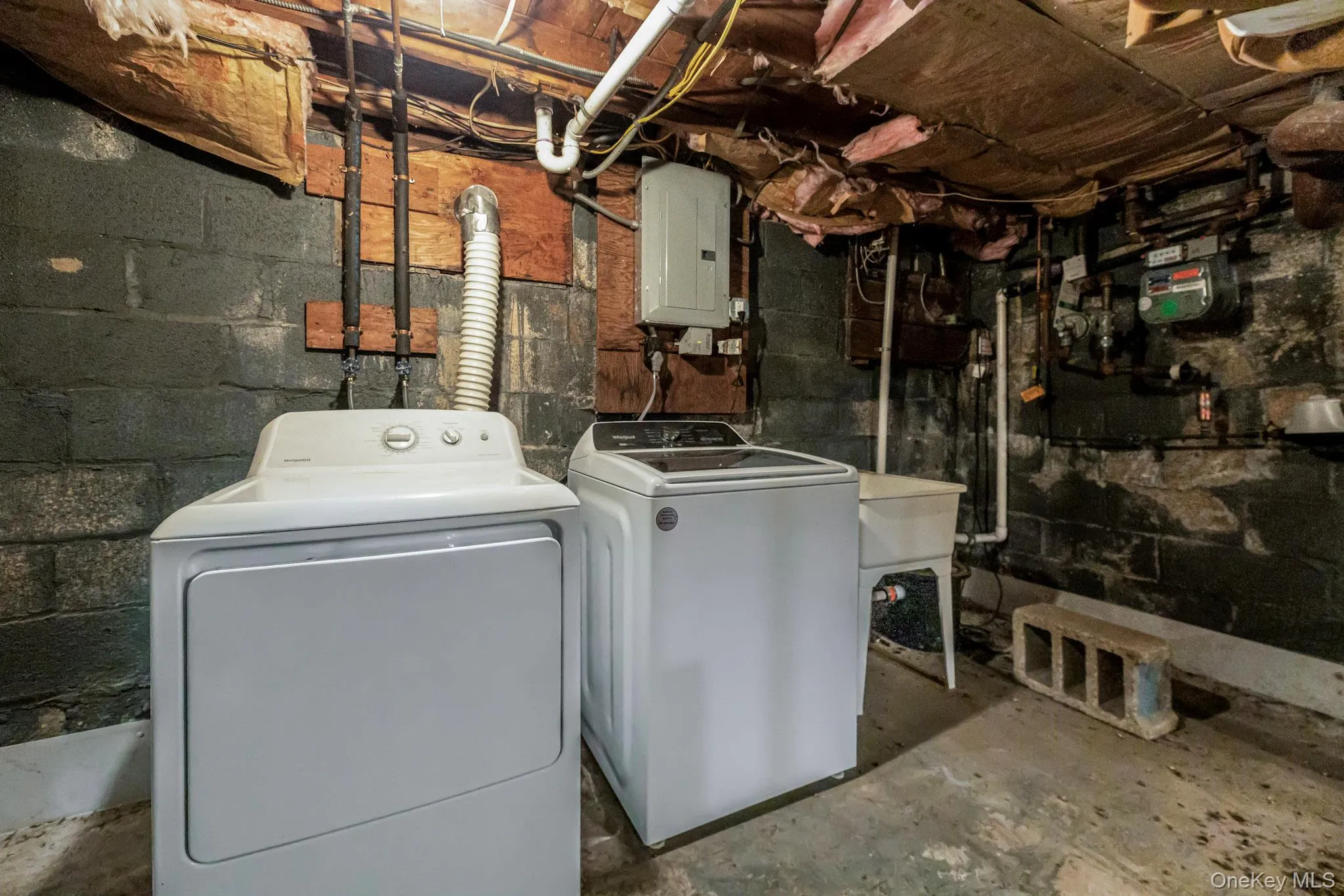 Laundry area featuring electric panel, unfinished concrete floors, and washing machine and dryer Laundry area featuring electric panel, unfinished concrete floors, and washing machine and dryer