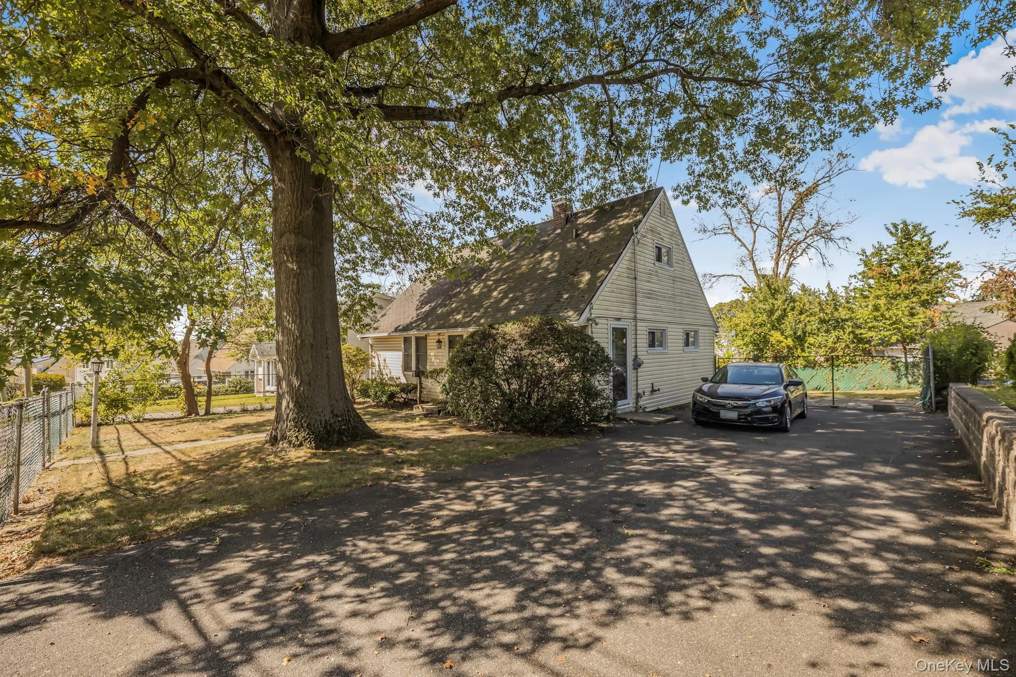 View of side of property featuring a chimney and asphalt driveway View of side of property featuring a chimney and asphalt driveway