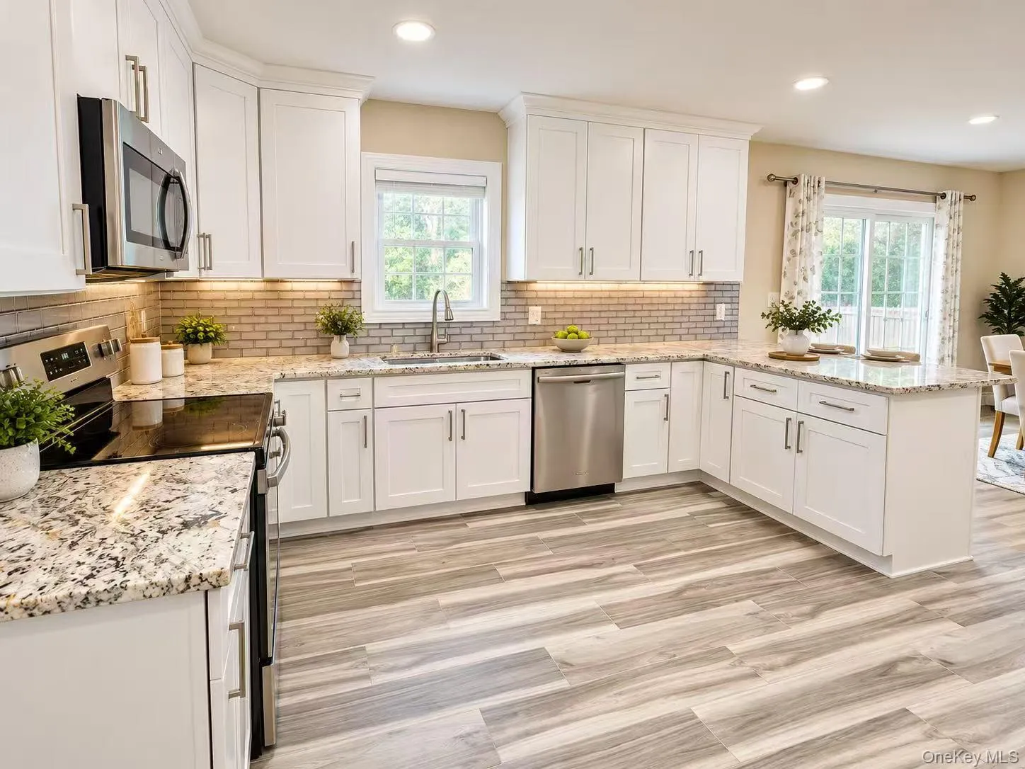 White cabinetry, stainless steel appliances, granite countertops, tile backsplash, and wood-finish flooring White cabinetry, stainless steel appliances, granite countertops, tile backsplash, and wood-finish flooring