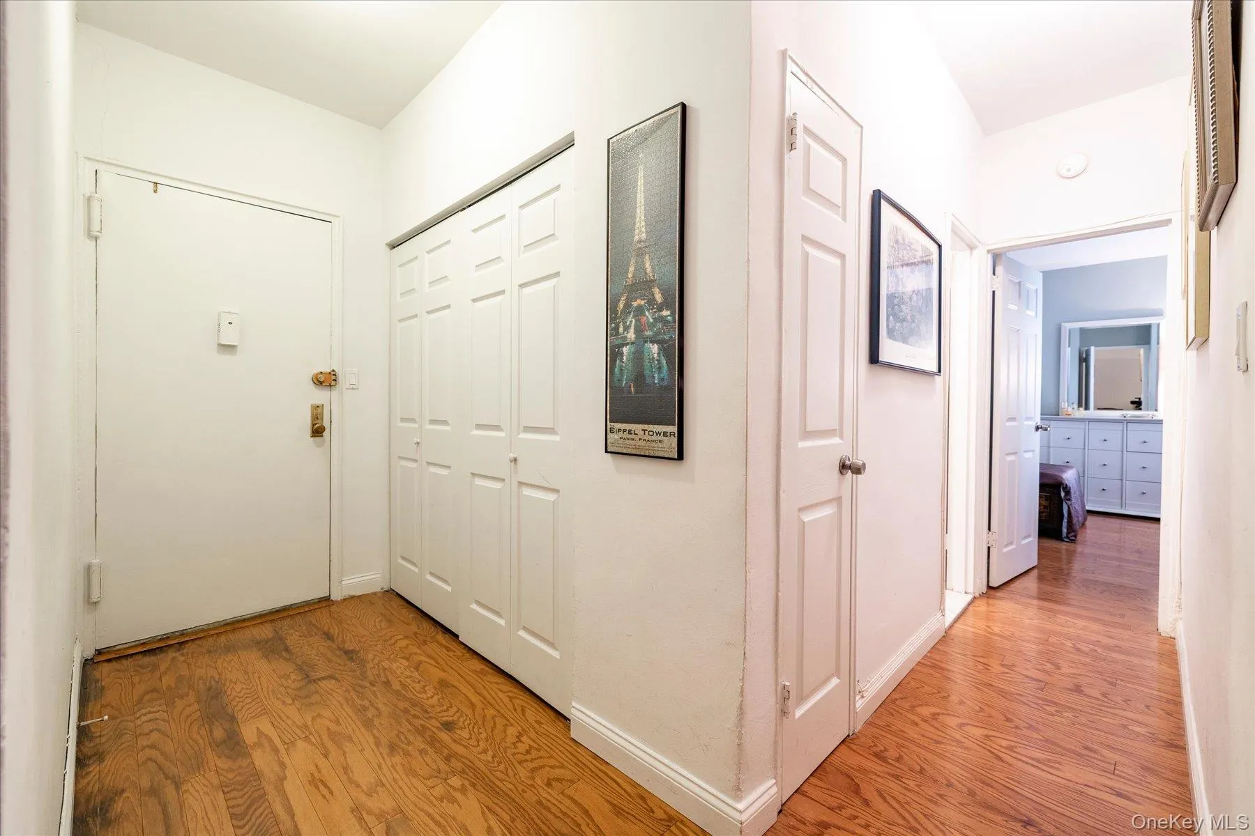 Entryway with wood-finish flooring, white paneled doors, and bi-fold closet doors Entryway with wood-finish flooring, white paneled doors, and bi-fold closet doors