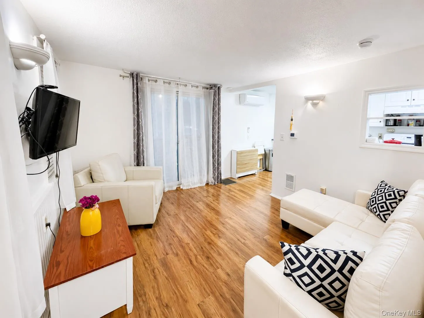 Wood-finish flooring throughout, white walls, and a sliding glass door with sheer and patterned drapes Wood-finish flooring throughout, white walls, and a sliding glass door with sheer and patterned drapes