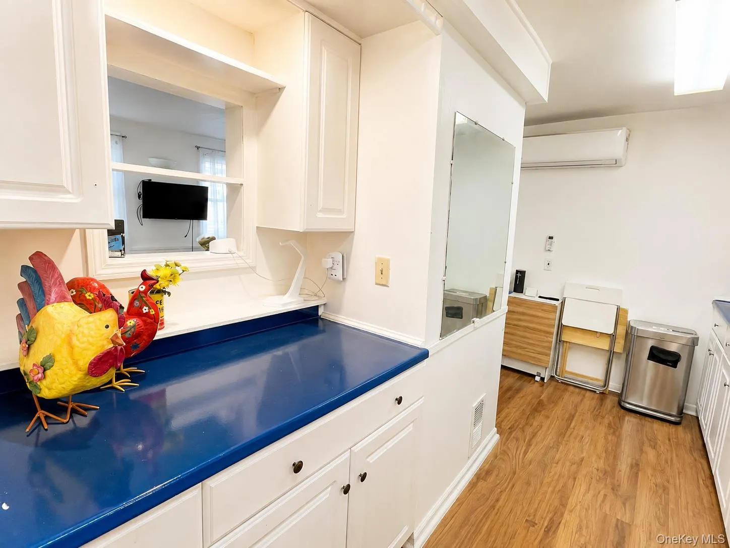 White shaker-style cabinetry with dark hardware and a pass-through window White shaker-style cabinetry with dark hardware and a pass-through window