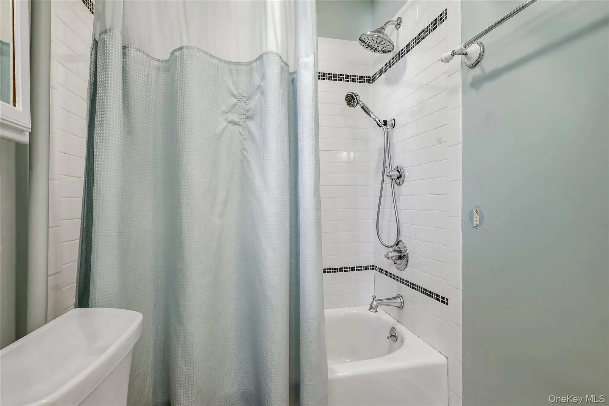Tub and shower combination with subway tile surround, decorative tile accent, and a dual-function shower head Tub and shower combination with subway tile surround, decorative tile accent, and a dual-function shower head