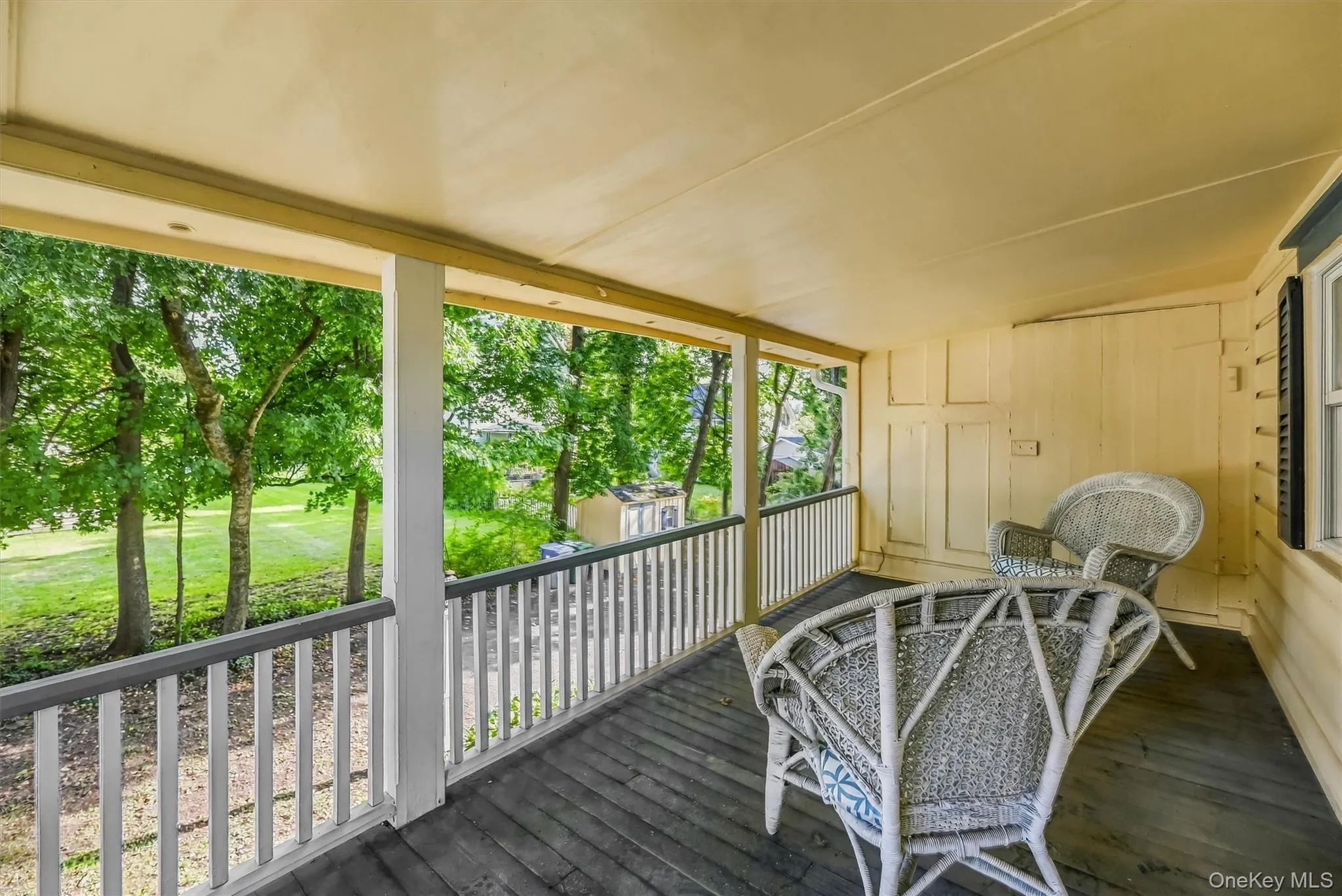 Spacious porch offering a peaceful view of the surrounding yard and mature trees Spacious porch offering a peaceful view of the surrounding yard and mature trees