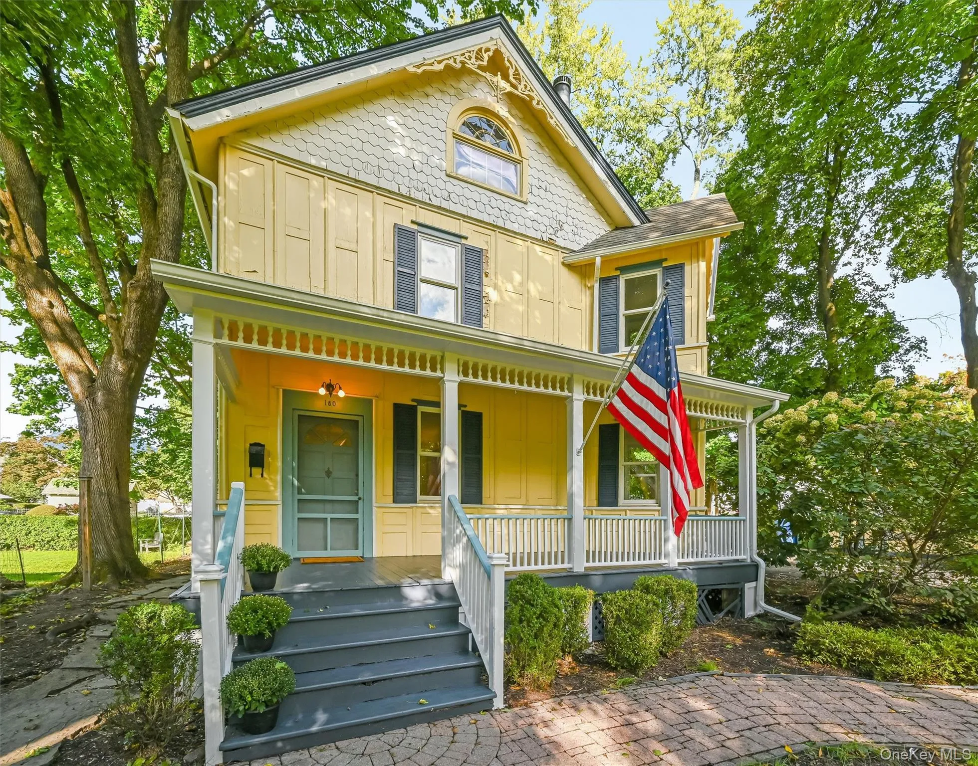Victorian-style exterior with yellow siding, covered front porch, decorative gable trim, and a brick paver walkway Victorian-style exterior with yellow siding, covered front porch, decorative gable trim, and a brick paver walkway