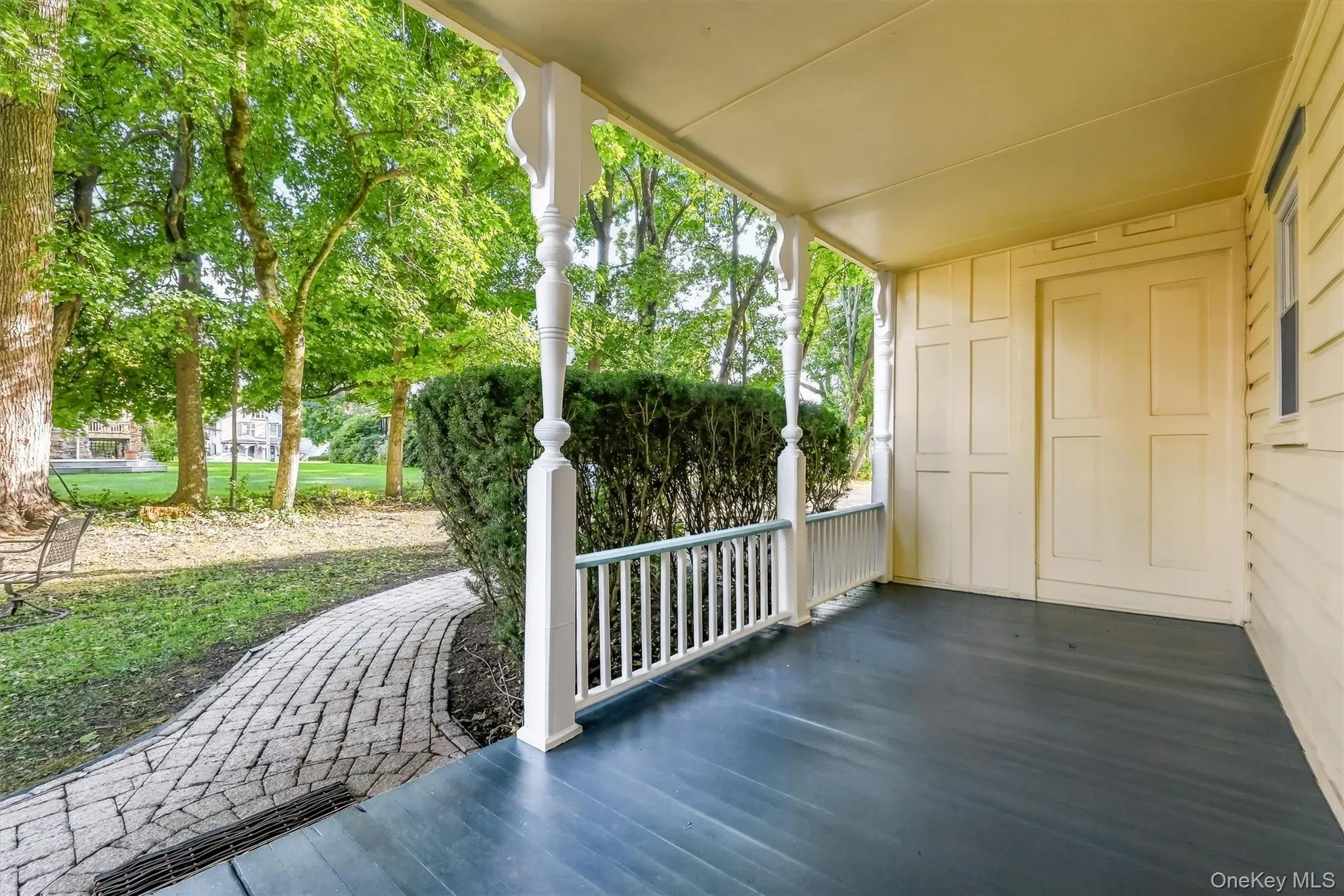 Covered porch with decorative columns, painted wood flooring, and paneling along the exterior wall Covered porch with decorative columns, painted wood flooring, and paneling along the exterior wall