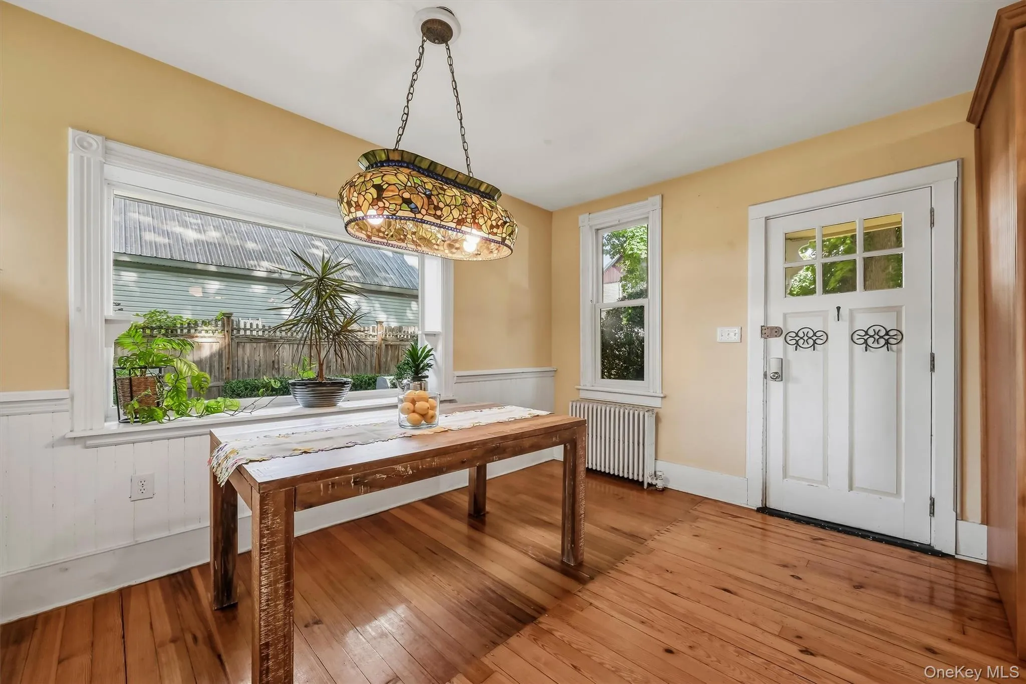 Bright dining area with hardwood floors, large picture window, and convenient exterior access Bright dining area with hardwood floors, large picture window, and convenient exterior access