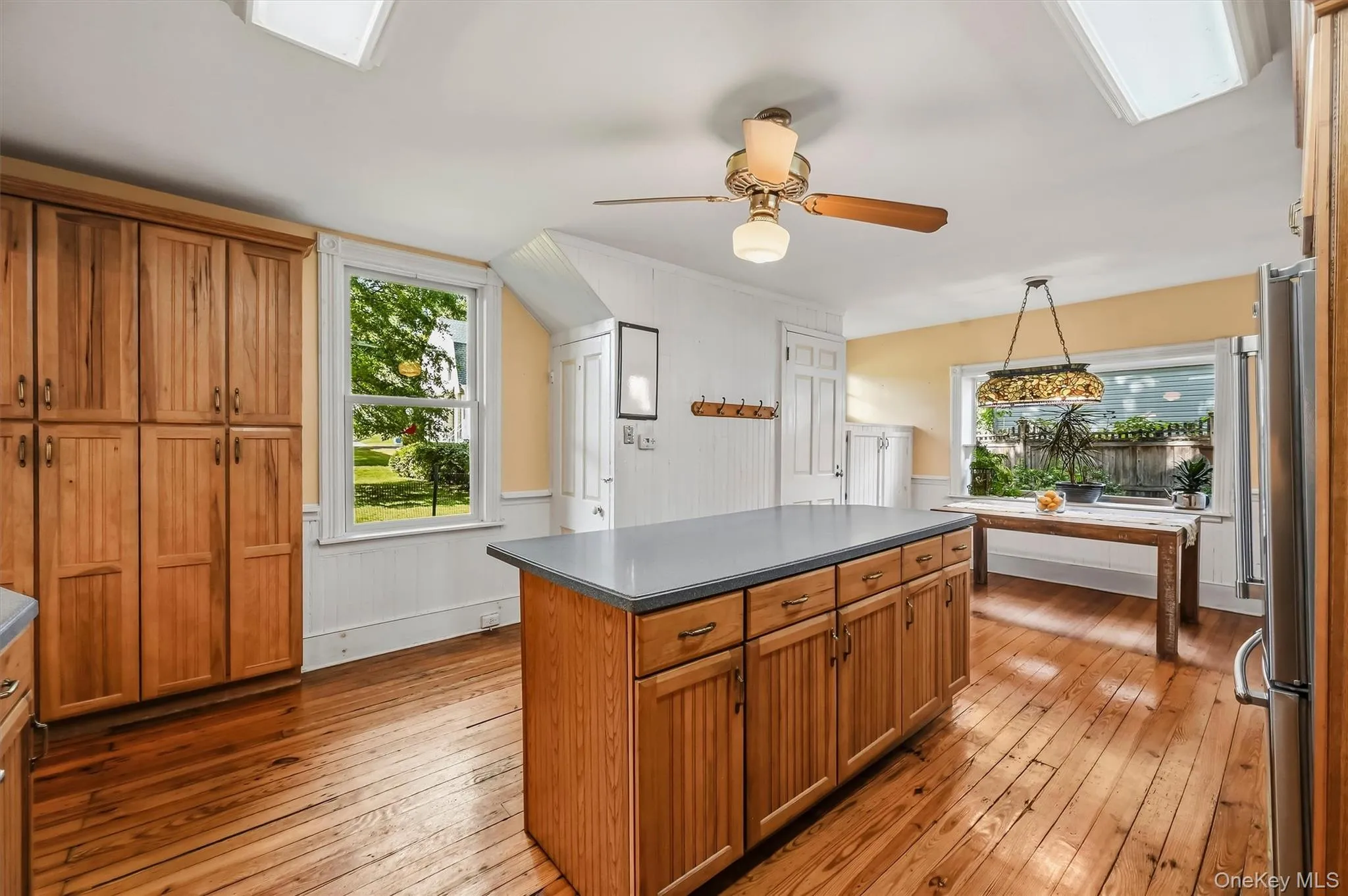 Spacious kitchen with center island, wood cabinetry, hardwood floors, and plenty of natural light Spacious kitchen with center island, wood cabinetry, hardwood floors, and plenty of natural light