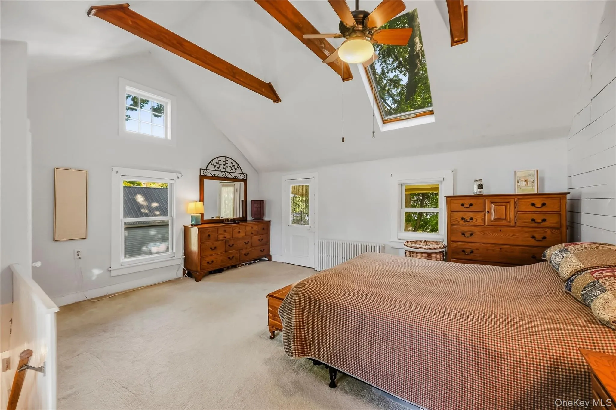 Spacious primary bedroom with vaulted ceiling, exposed wood beams, skylights, and abundant natural light Spacious primary bedroom with vaulted ceiling, exposed wood beams, skylights, and abundant natural light