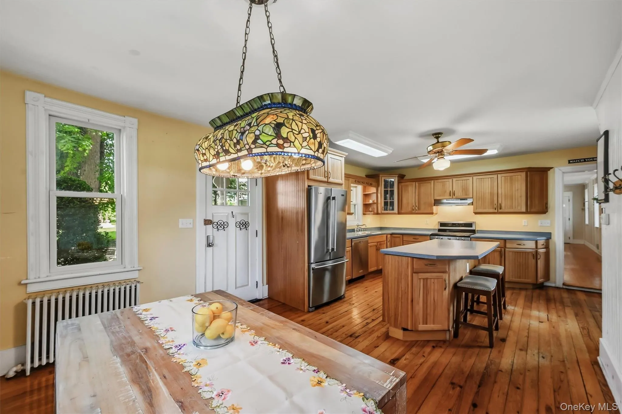 Open kitchen and dining area with center island, wood cabinetry, hardwood floors, and ample natural light Open kitchen and dining area with center island, wood cabinetry, hardwood floors, and ample natural light