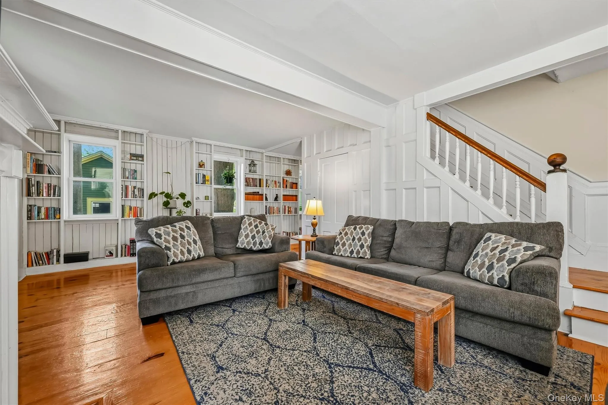 Spacious living room with wood floors, built-in bookshelves and staircase access Spacious living room with wood floors, built-in bookshelves and staircase access