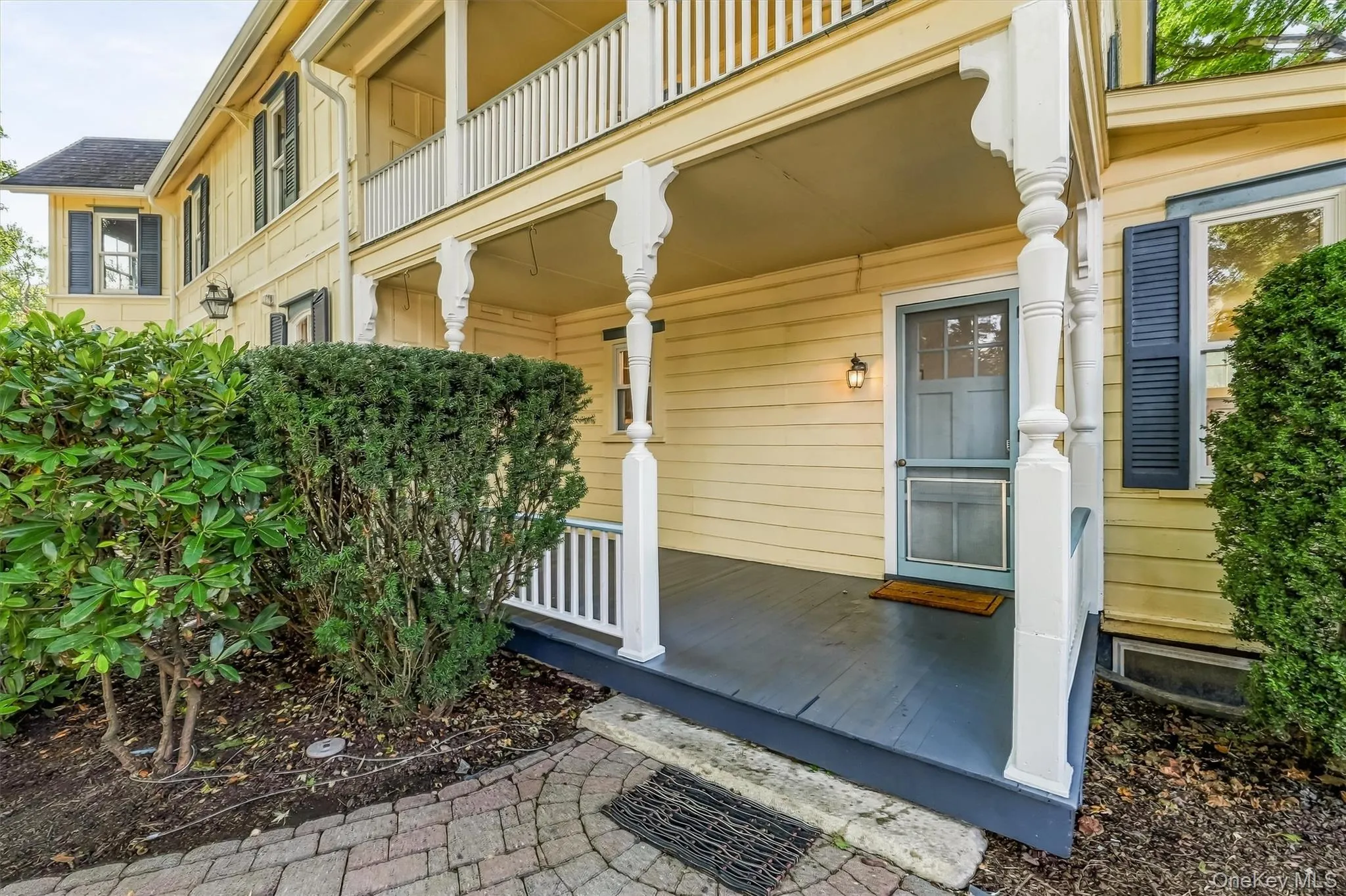 Welcoming covered porch with decorative columns and brick walkway Welcoming covered porch with decorative columns and brick walkway