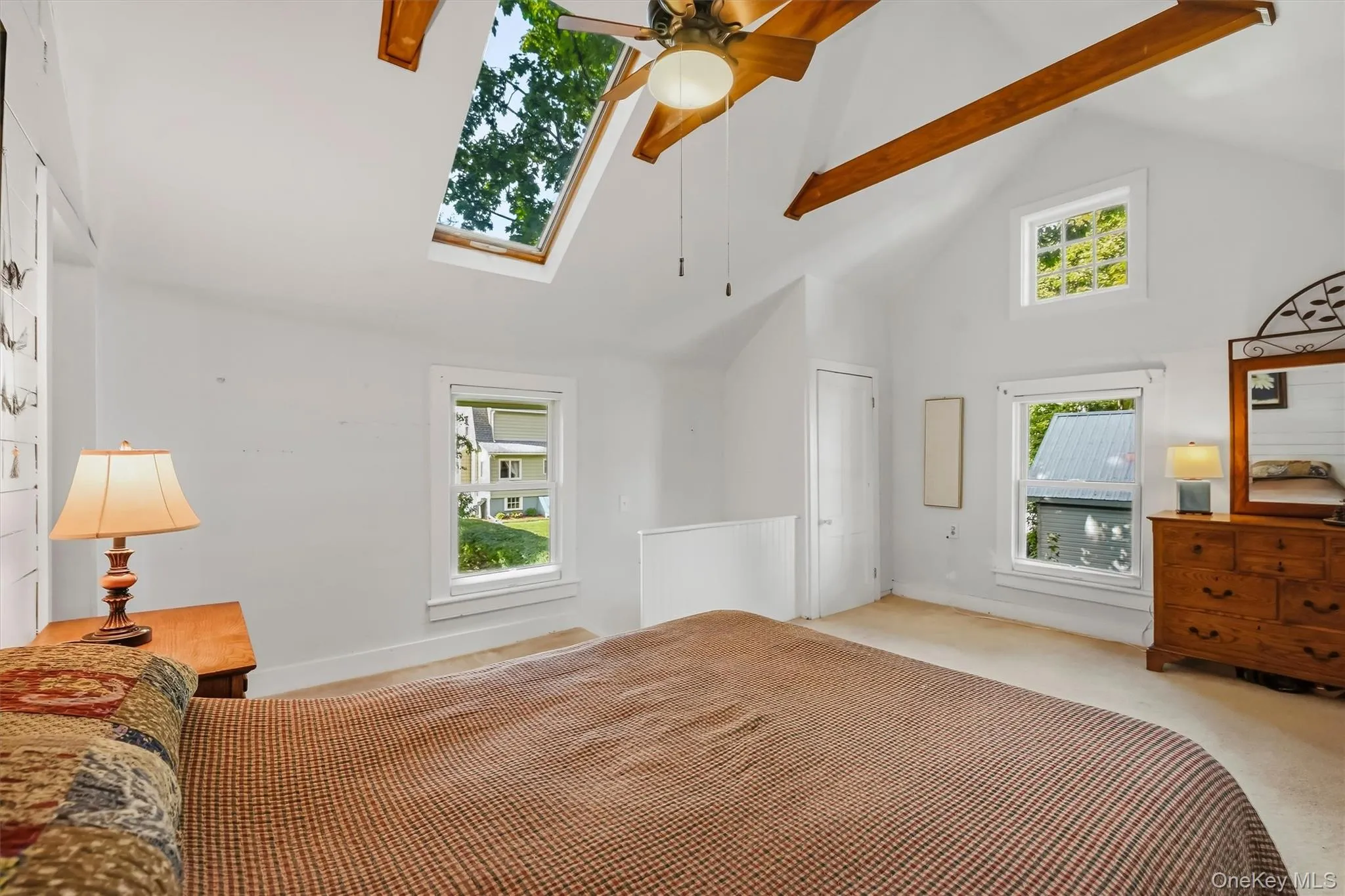 Bright primary bedroom with multiple windows and distinctive vaulted ceiling Bright primary bedroom with multiple windows and distinctive vaulted ceiling