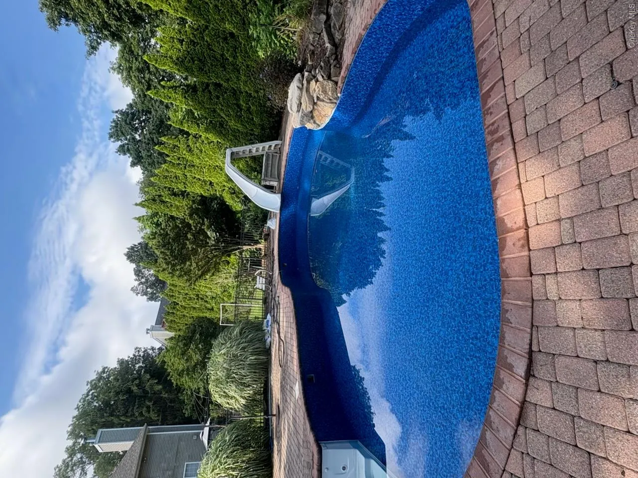 Swimming pool with a patterned blue liner, surrounded by brick paver coping and a stone border Swimming pool with a patterned blue liner, surrounded by brick paver coping and a stone border
