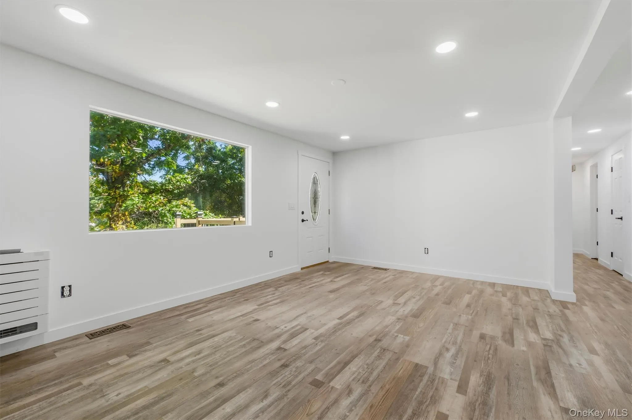 Dining Room with recessed lighting illuminates the open living area featuring wood-finish flooring, a large picture window, and a white entry door with frosted glass Dining Room with recessed lighting illuminates the open living area featuring wood-finish flooring, a large picture window, and a white entry door with frosted glass