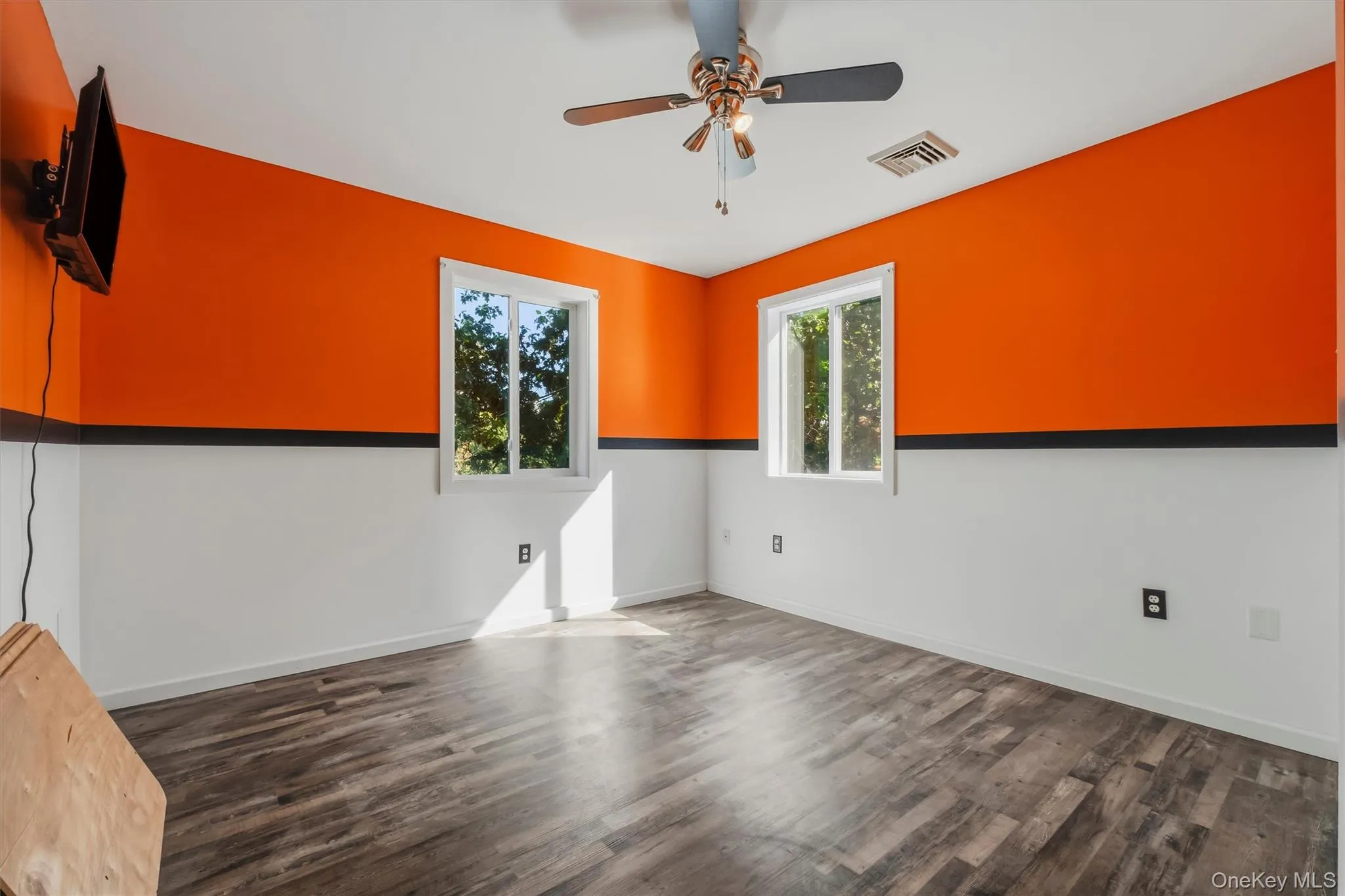 Bedroom 2 with Wood-finish flooring with a two-tone wall design, two windows, and a ceiling fan Bedroom 2 with Wood-finish flooring with a two-tone wall design, two windows, and a ceiling fan