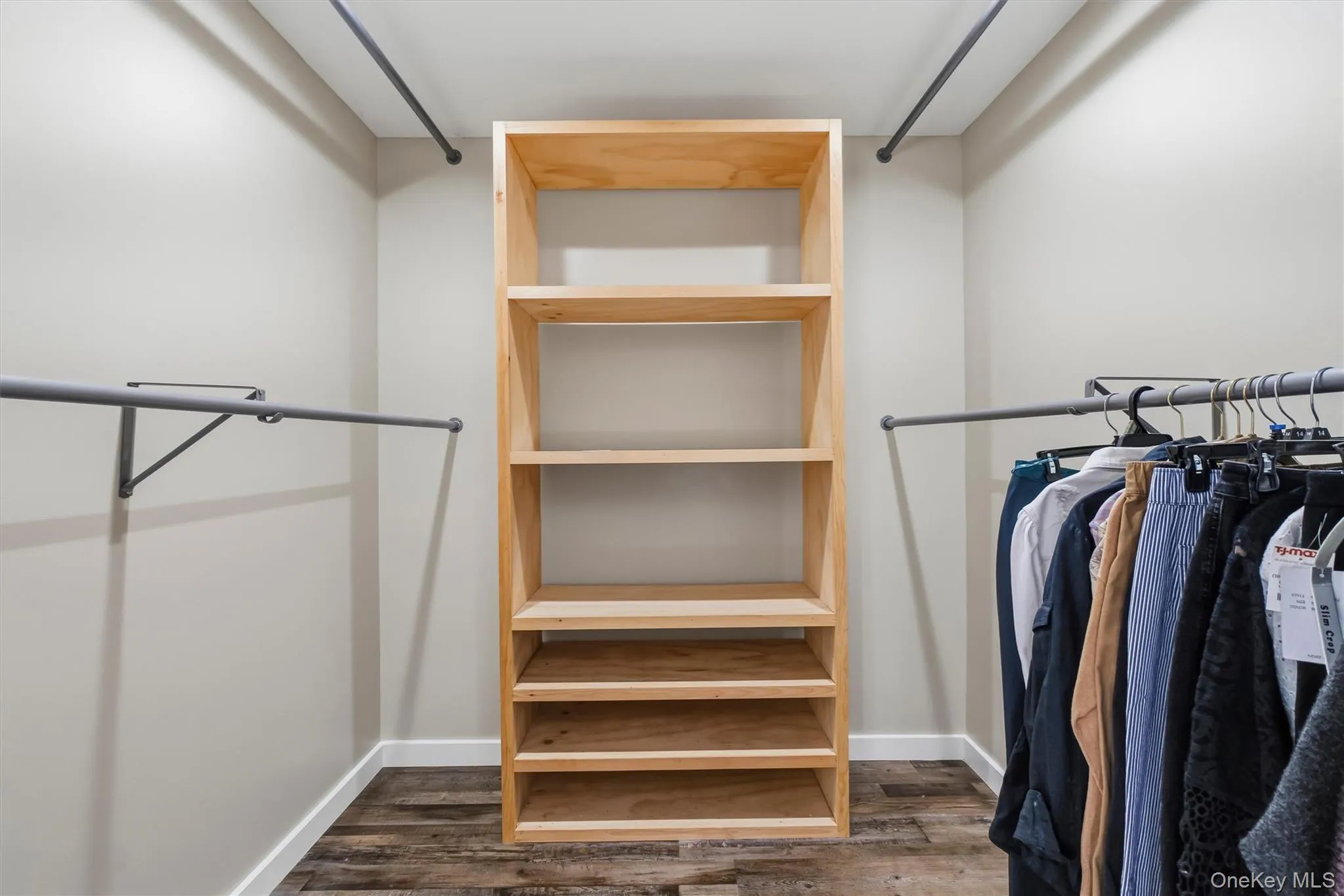 Walk-in closet featuring wood-finish flooring, built-in shelving, and multiple clothing rods Walk-in closet featuring wood-finish flooring, built-in shelving, and multiple clothing rods