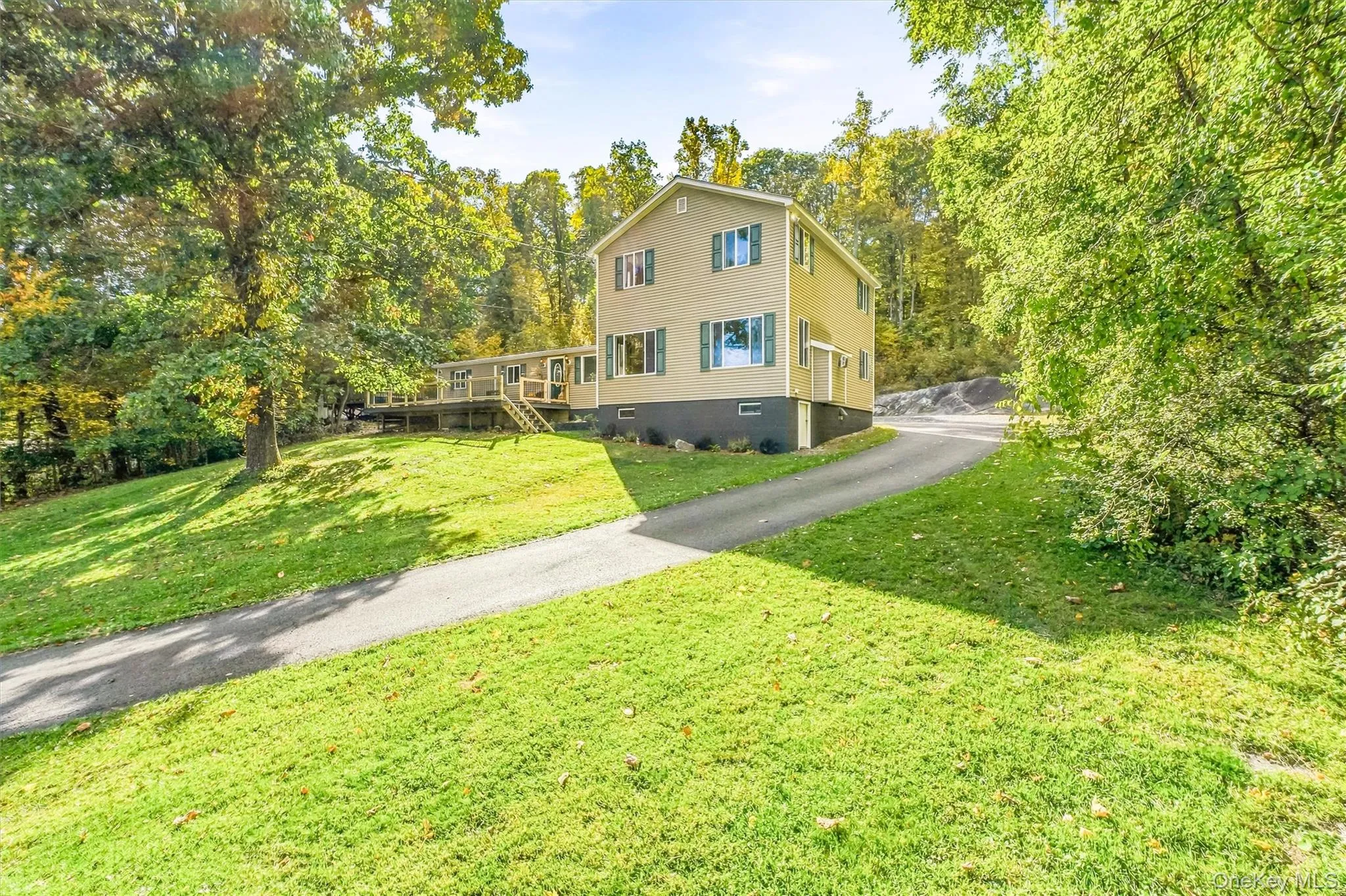 Two-story residence with siding exterior, green window shutters, and a sloped asphalt driveway Two-story residence with siding exterior, green window shutters, and a sloped asphalt driveway