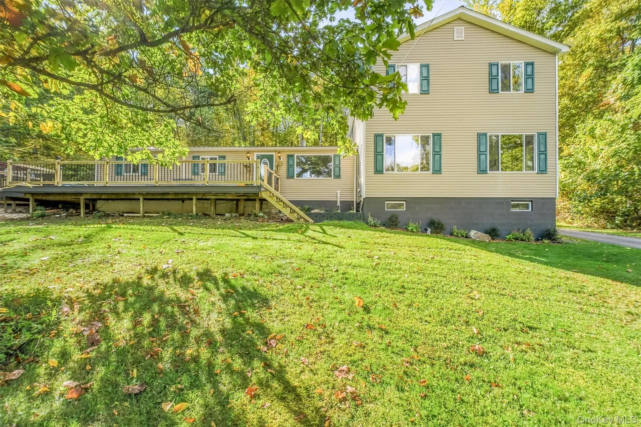 Spacious exterior deck with wood railing, set against a backdrop of mature trees and a manicured lawn Spacious exterior deck with wood railing, set against a backdrop of mature trees and a manicured lawn