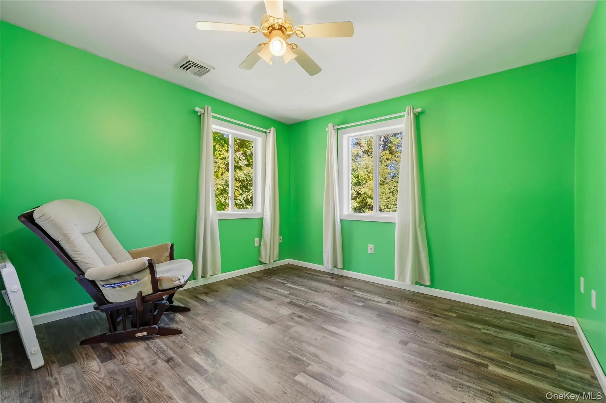 Bedroom 3 featuring wood-finish flooring, two windows, and a ceiling fan with integrated lighting Bedroom 3 featuring wood-finish flooring, two windows, and a ceiling fan with integrated lighting