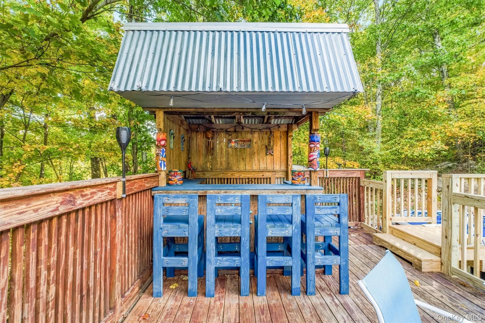 Outdoor bar structure featuring a corrugated metal roof, wood construction, and a bar counter with seating Outdoor bar structure featuring a corrugated metal roof, wood construction, and a bar counter with seating