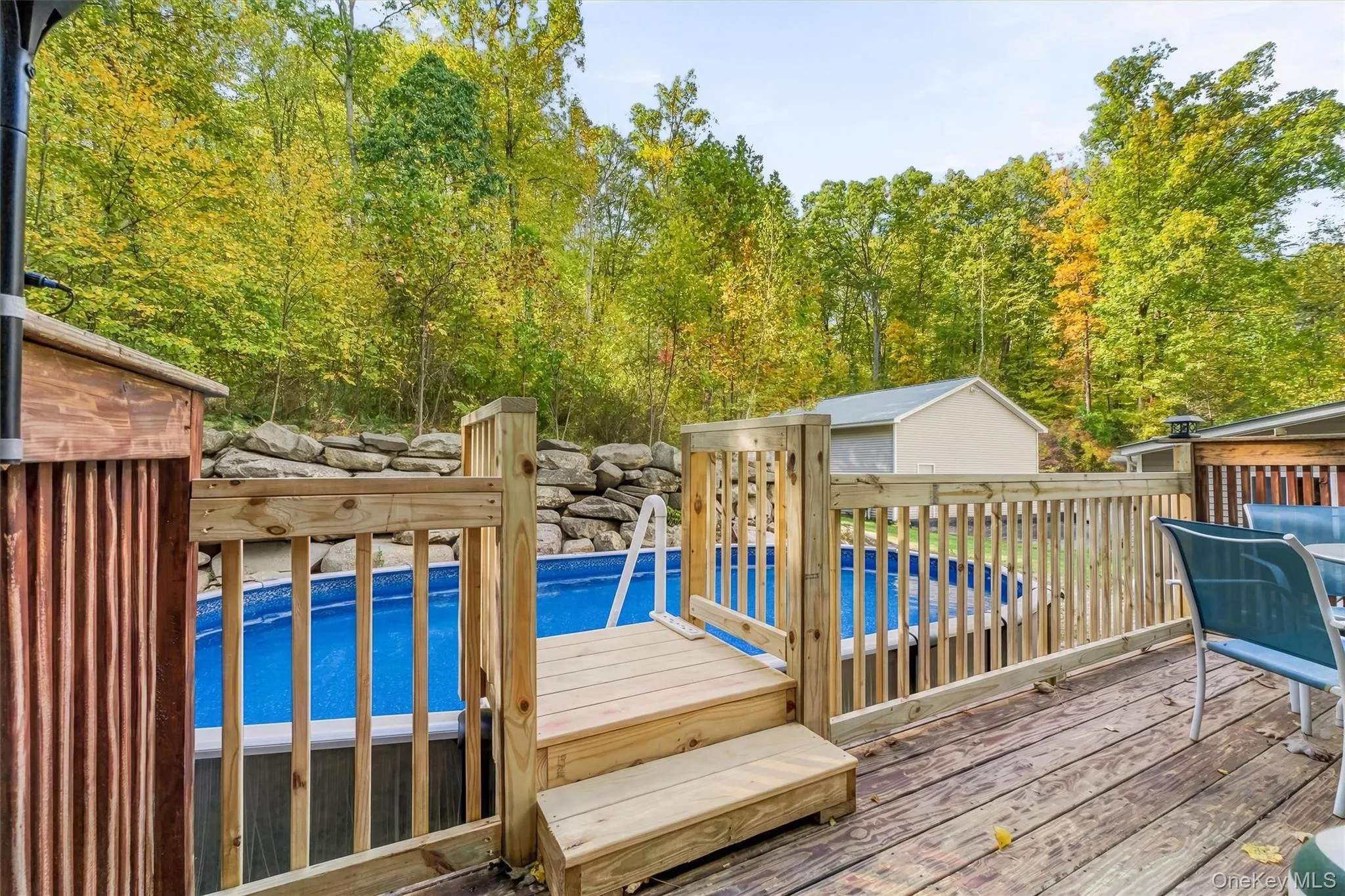 Expansive wood deck with a built-in above-ground pool, surrounded by natural rock landscaping and mature trees Expansive wood deck with a built-in above-ground pool, surrounded by natural rock landscaping and mature trees