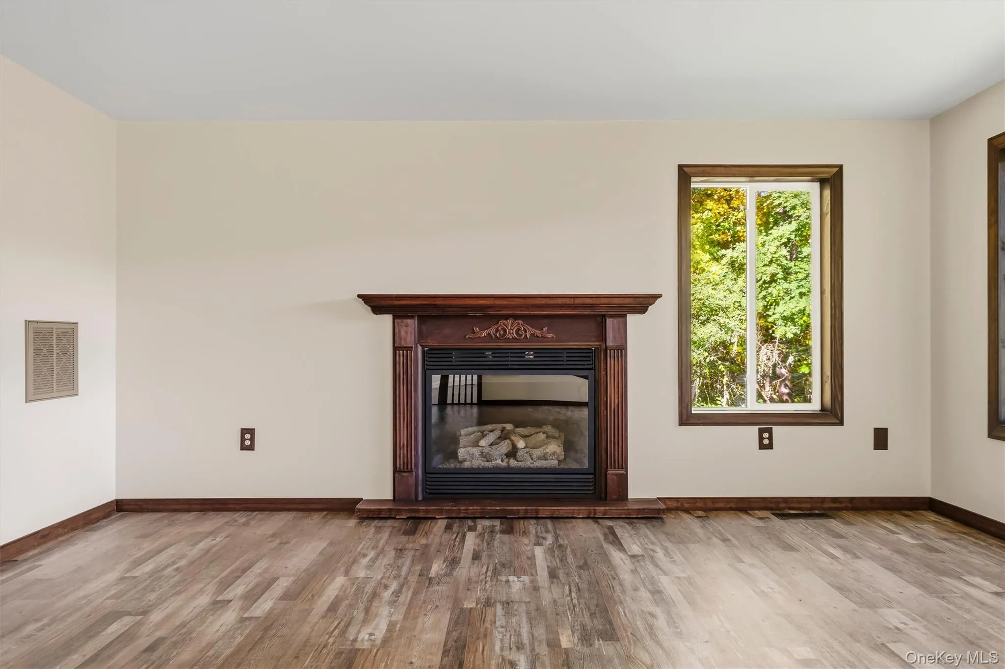 Wood-finish flooring with a propane fireplace and a carved wood mantelpiece Wood-finish flooring with a propane fireplace and a carved wood mantelpiece