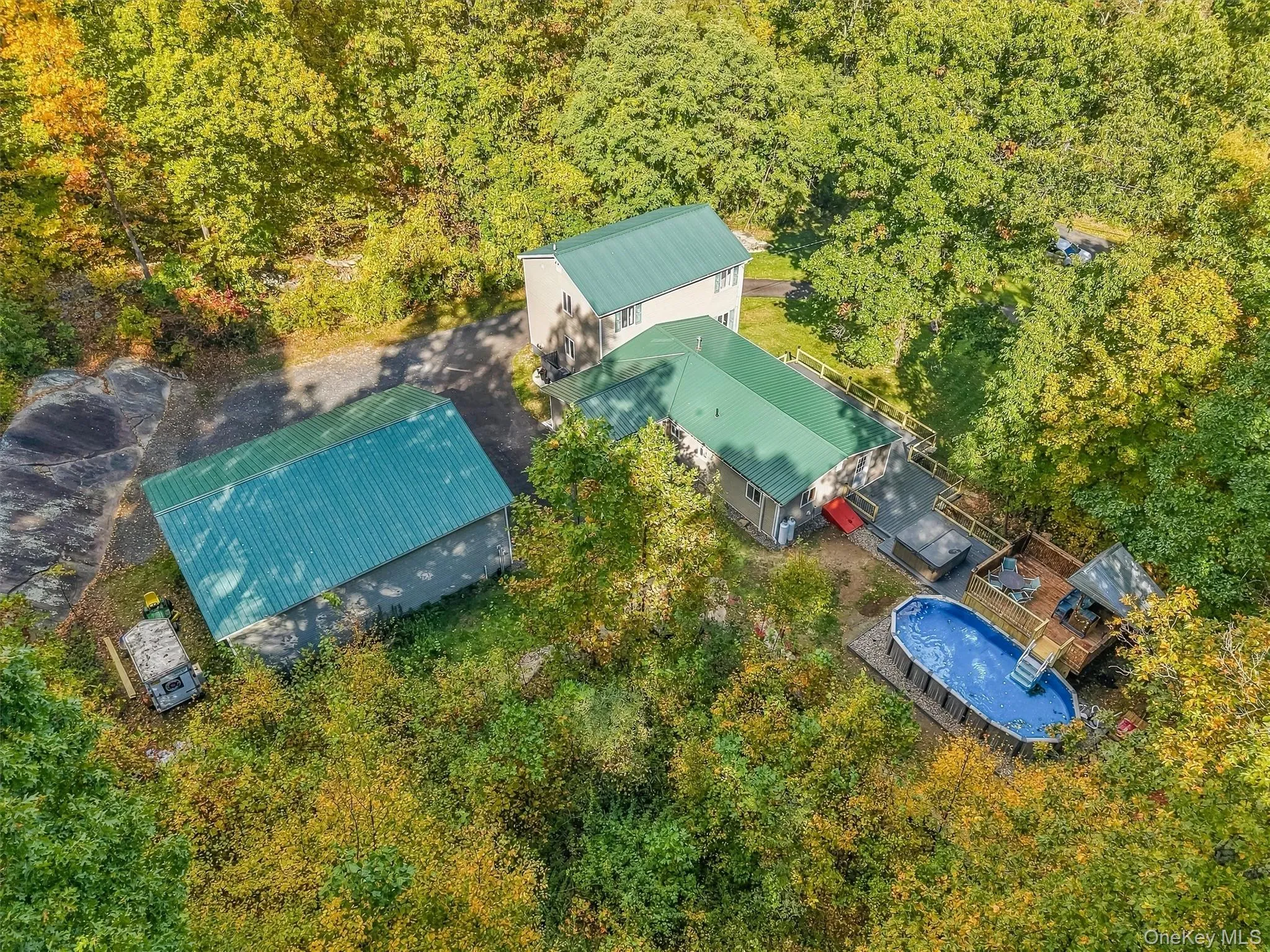Multiple structures with green metal roofs, extensive decking, and an above-ground pool Multiple structures with green metal roofs, extensive decking, and an above-ground pool