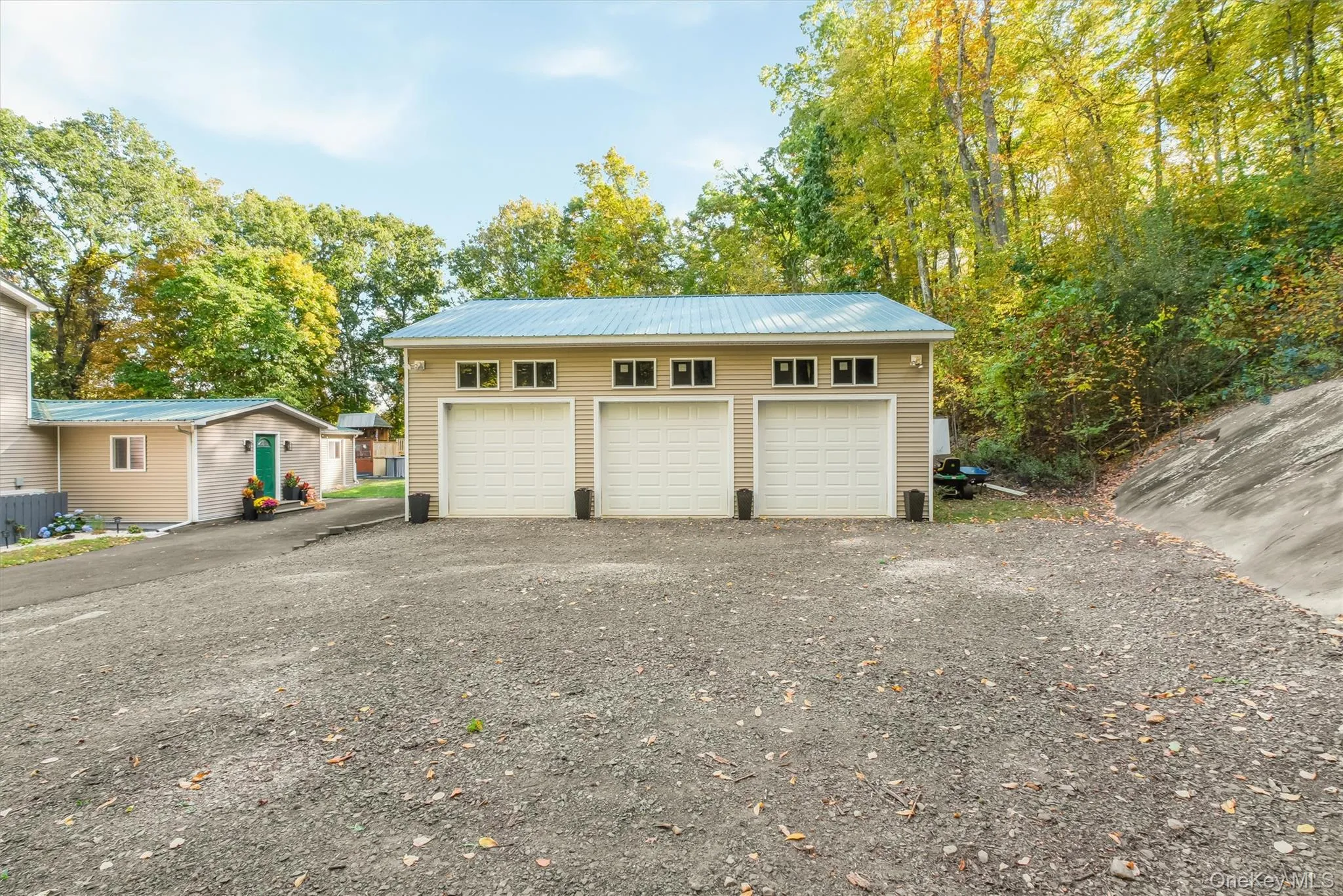 Three-car garage with overhead doors and transom windows, featuring a metal roof and siding exterior Three-car garage with overhead doors and transom windows, featuring a metal roof and siding exterior
