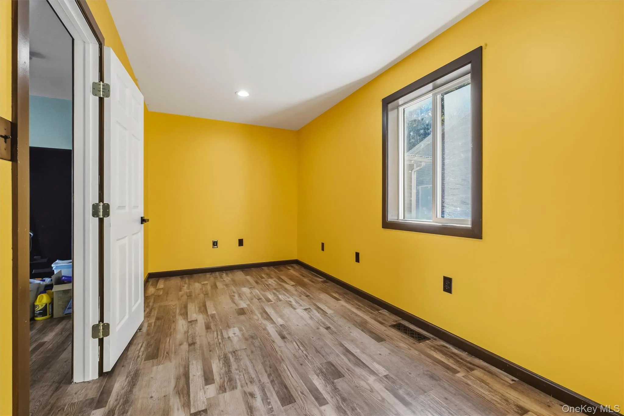 Office with Wood-finish flooring, recessed ceiling lighting, and a single window with dark trim Office with Wood-finish flooring, recessed ceiling lighting, and a single window with dark trim