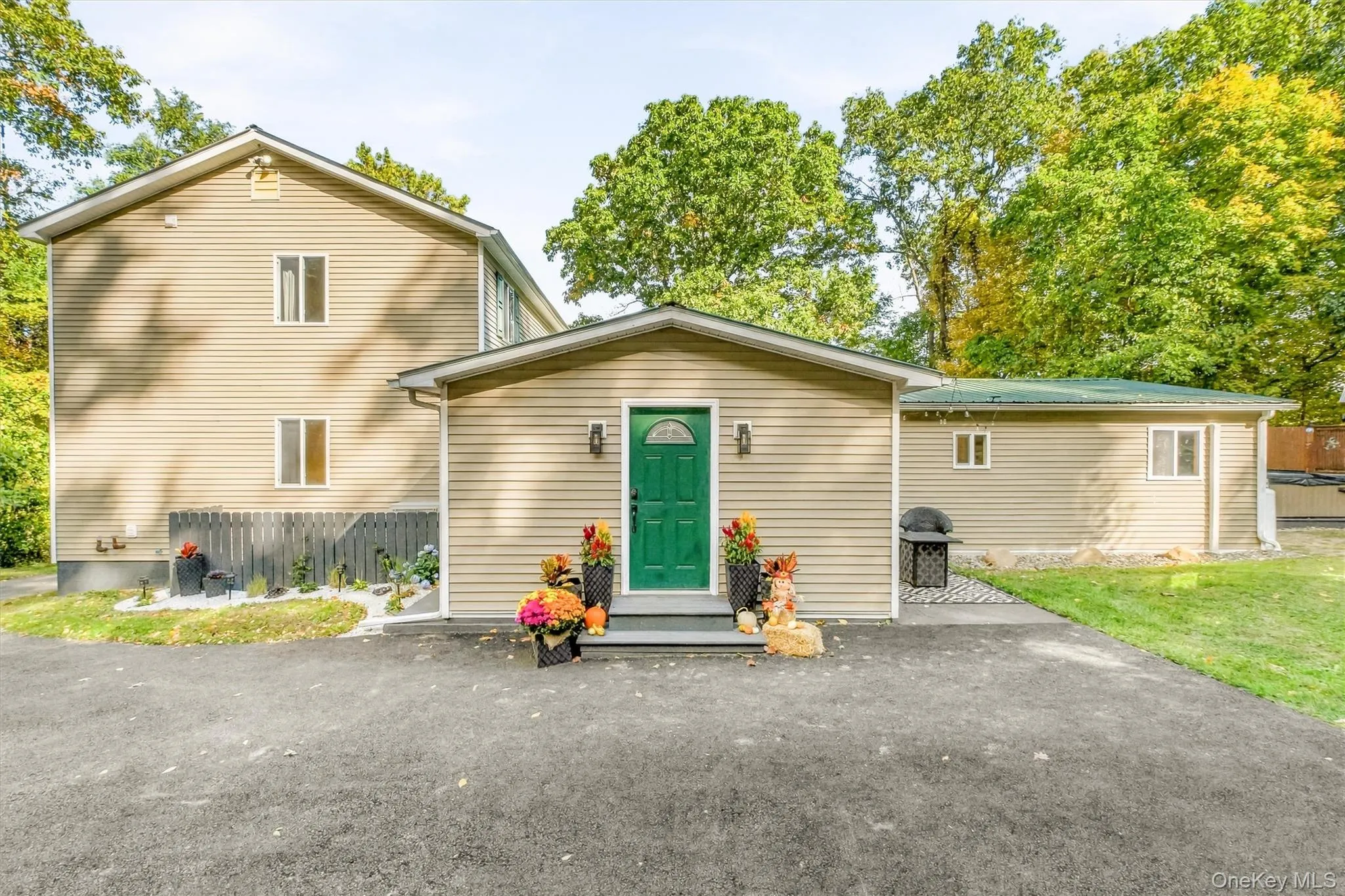 Rear view of home featuring neutral-toned siding, a vibrant green entry door, and a paved driveway Rear view of home featuring neutral-toned siding, a vibrant green entry door, and a paved driveway