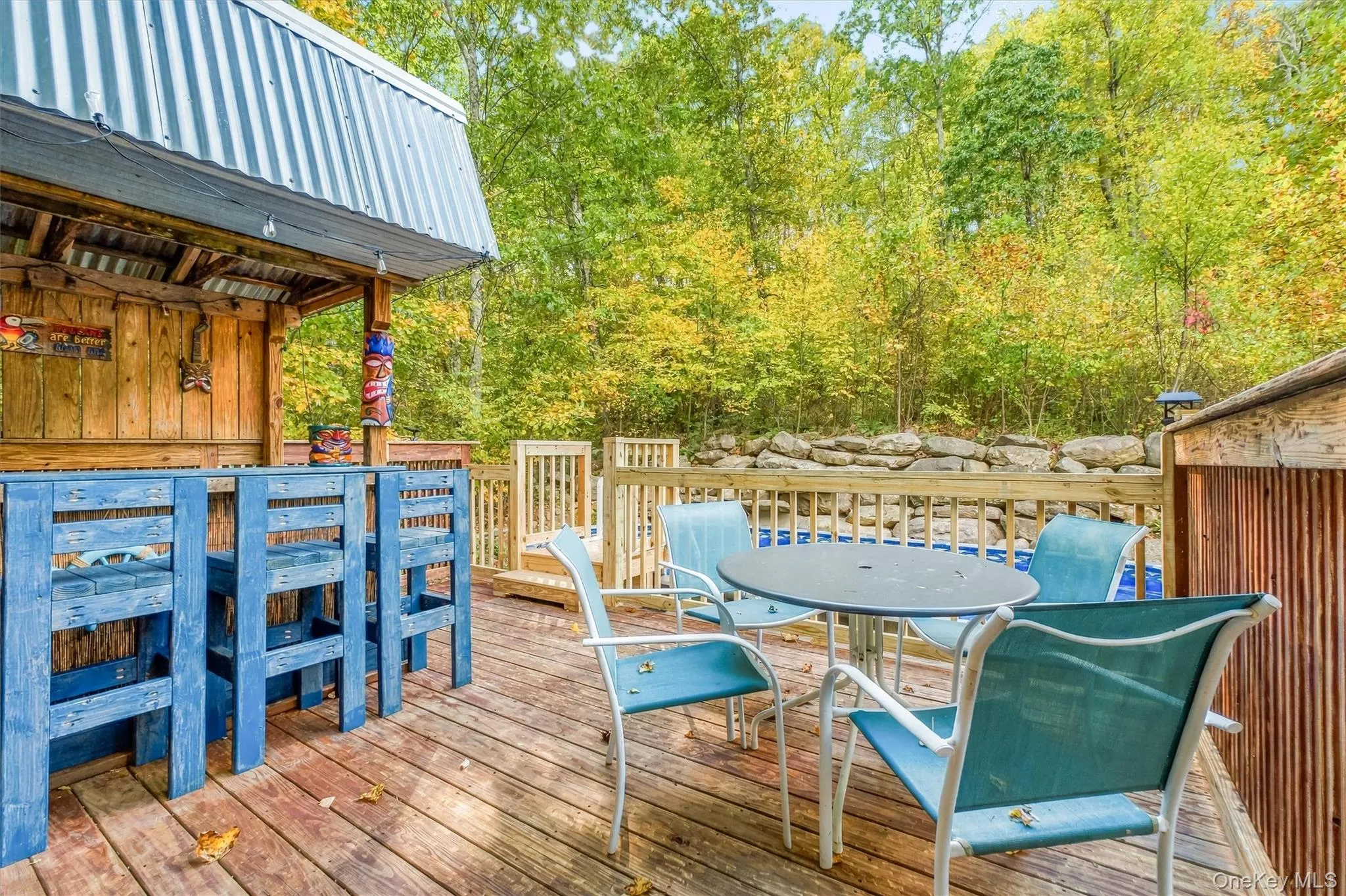 Spacious wood deck with a built-in bar, wood railing, and surrounding mature trees Spacious wood deck with a built-in bar, wood railing, and surrounding mature trees