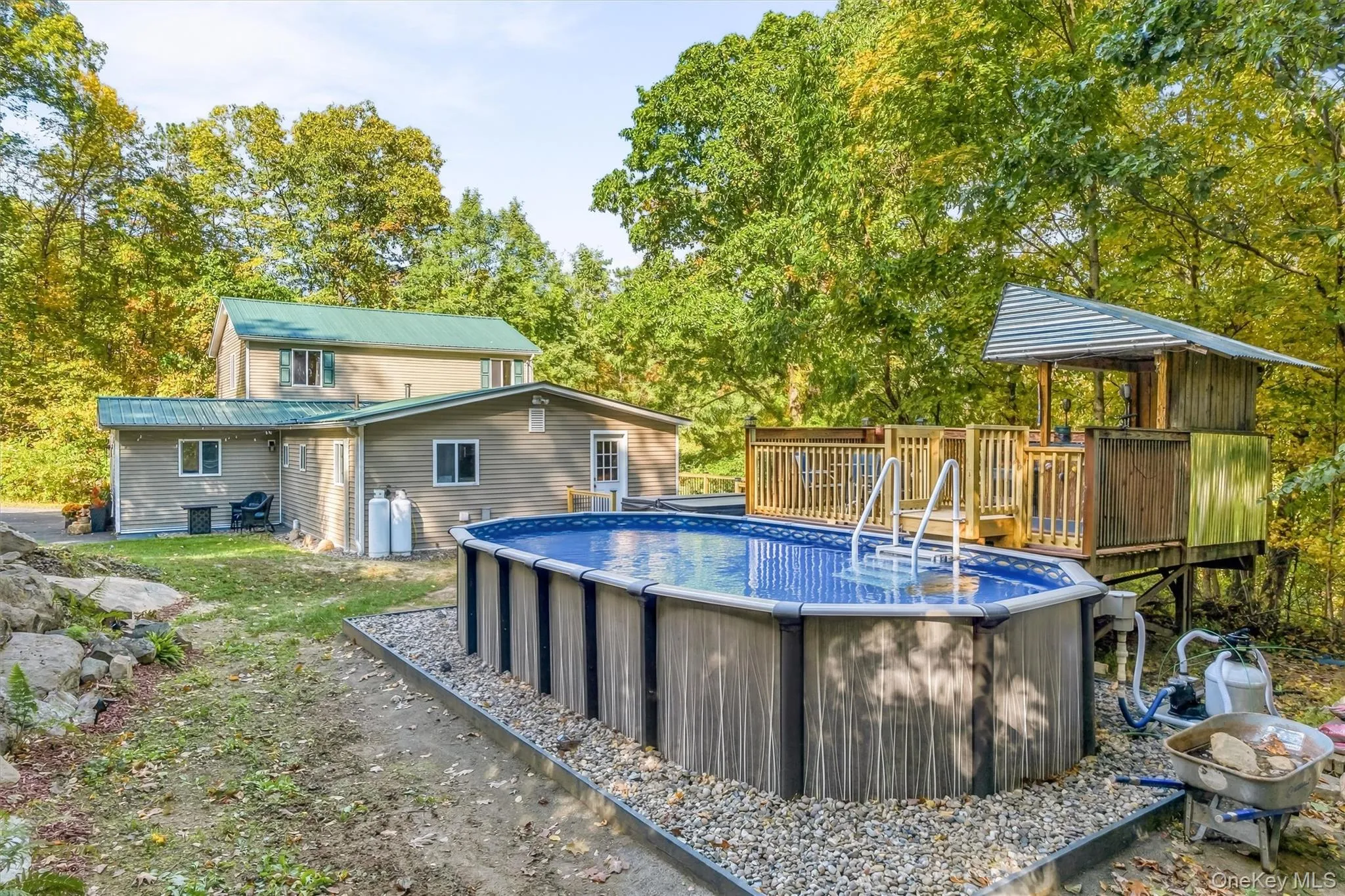 Above-ground pool with surrounding gravel, multi-level wooden deck, and elevated wooden structure Above-ground pool with surrounding gravel, multi-level wooden deck, and elevated wooden structure