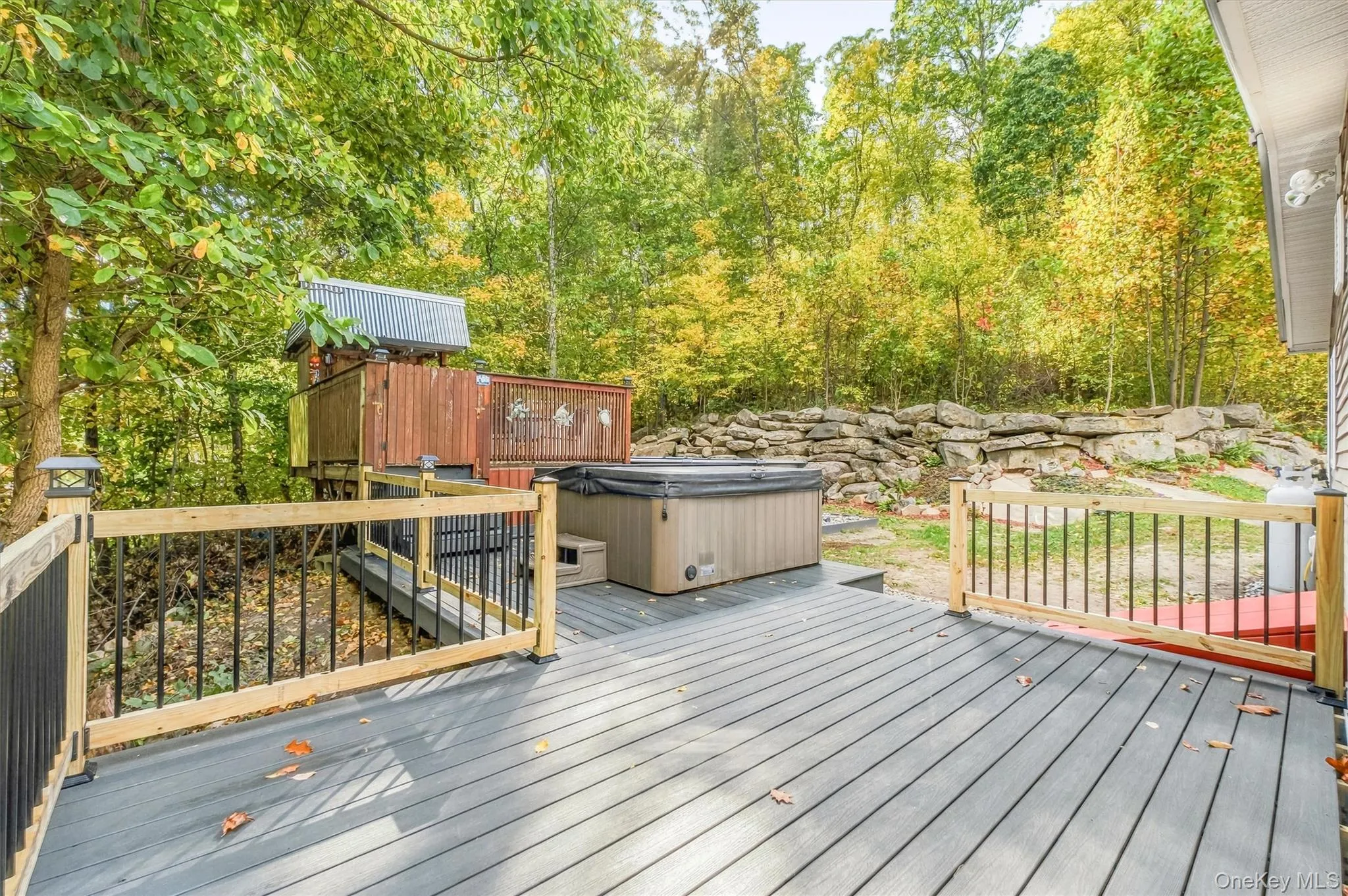 Expansive outdoor deck featuring composite decking, wood railings with black balusters, a built-in hot tub, and a multi-level play structure Expansive outdoor deck featuring composite decking, wood railings with black balusters, a built-in hot tub, and a multi-level play structure