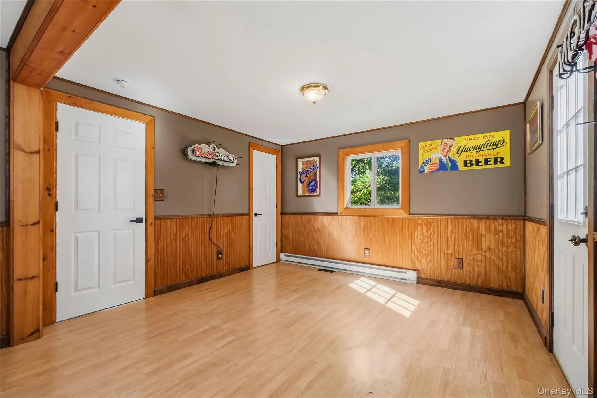Wood-finish flooring with natural light, a window with wood trim, and a ceiling-mounted light fixture Wood-finish flooring with natural light, a window with wood trim, and a ceiling-mounted light fixture