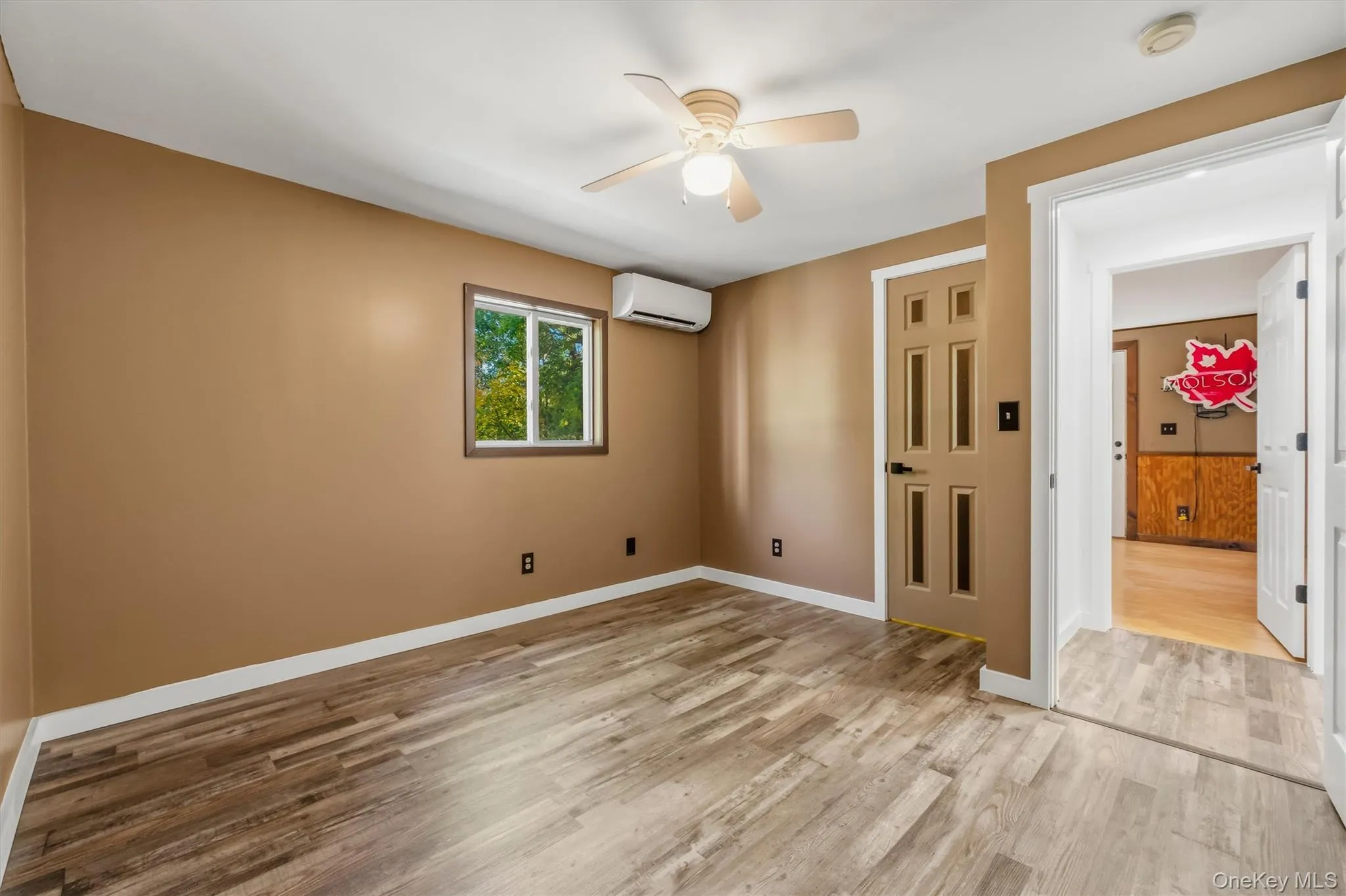 Wood-finish flooring with a ceiling fan, window, and split-system climate control unit Wood-finish flooring with a ceiling fan, window, and split-system climate control unit