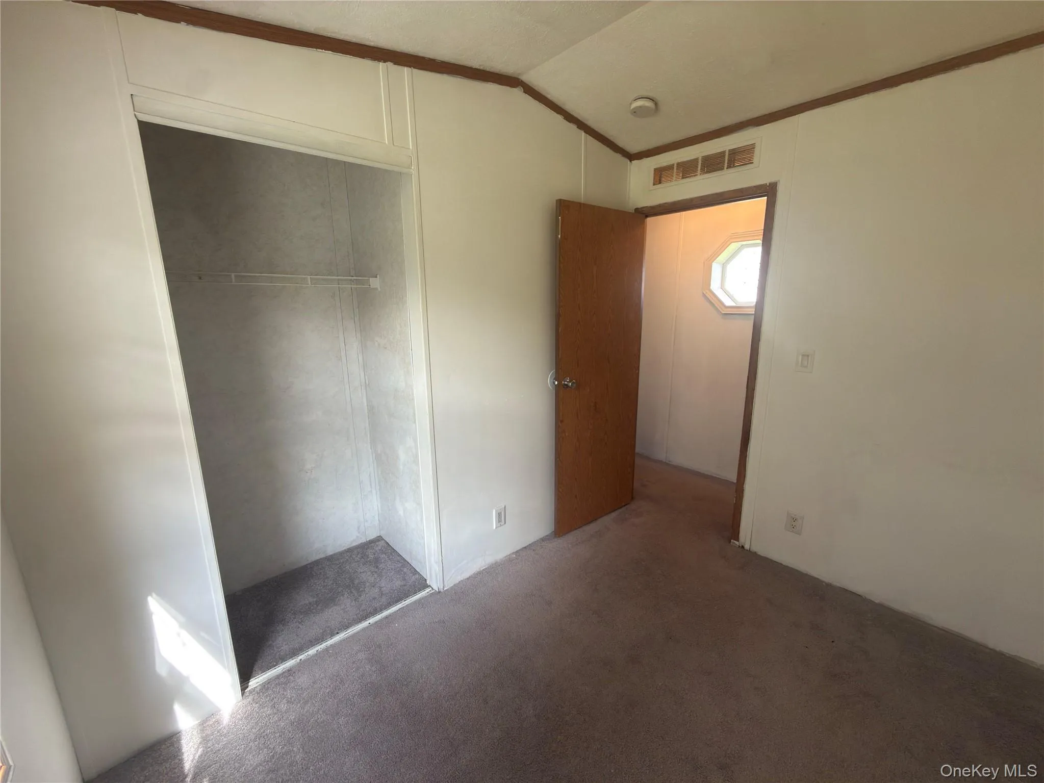 Carpeted flooring, built-in closet with wire shelving, interior door with hardware, wall-mounted light switch Carpeted flooring, built-in closet with wire shelving, interior door with hardware, wall-mounted light switch