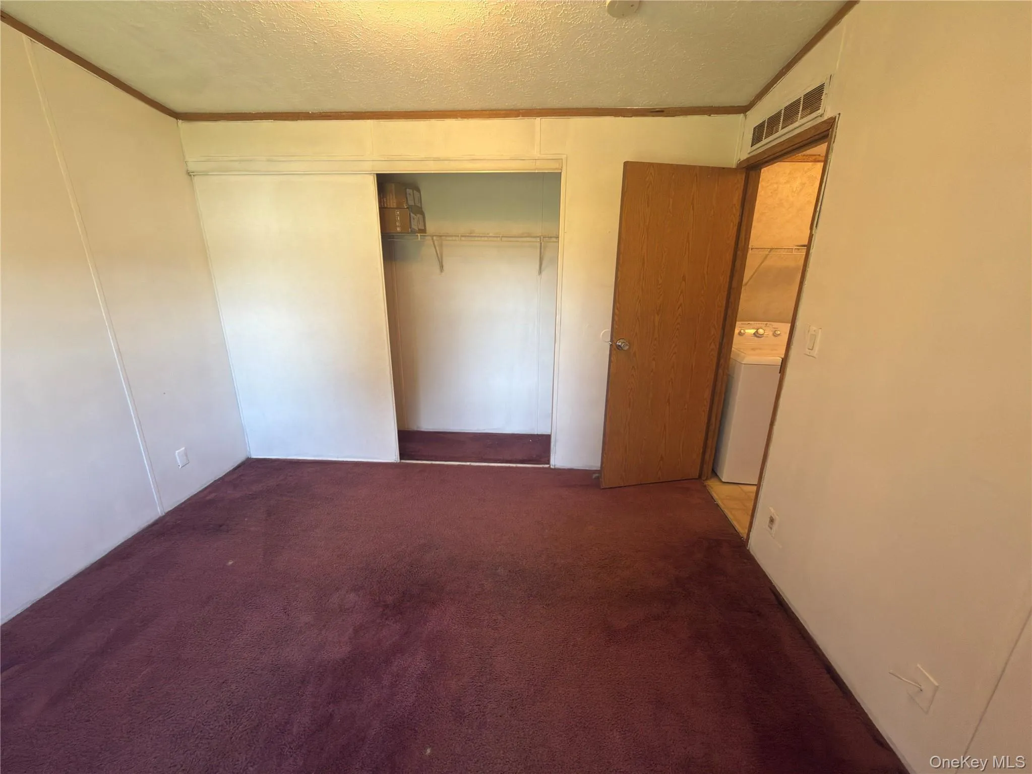 Room with wall-to-wall carpeting, wood-paneled walls, and a recessed closet with sliding doors Room with wall-to-wall carpeting, wood-paneled walls, and a recessed closet with sliding doors