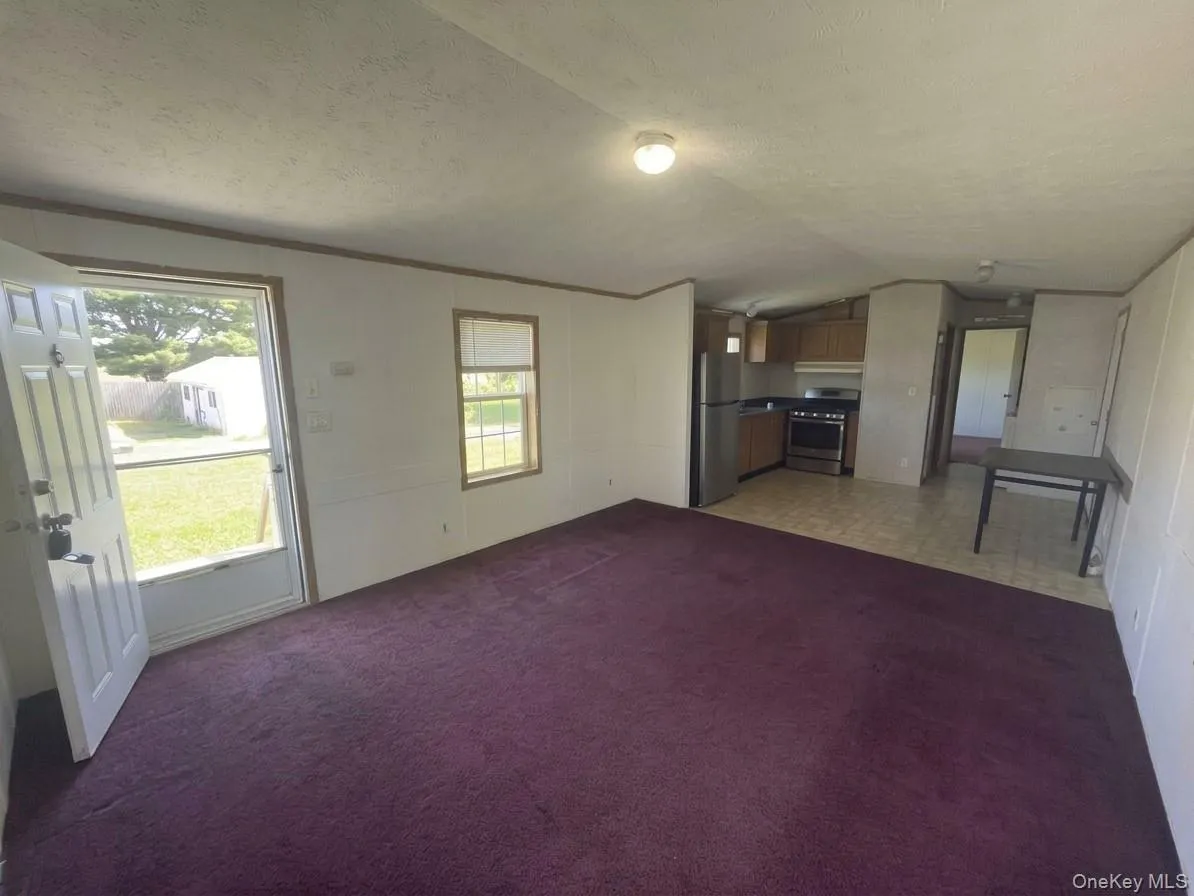 Open concept living area with purple carpeting, white walls, and wood trim accents Open concept living area with purple carpeting, white walls, and wood trim accents