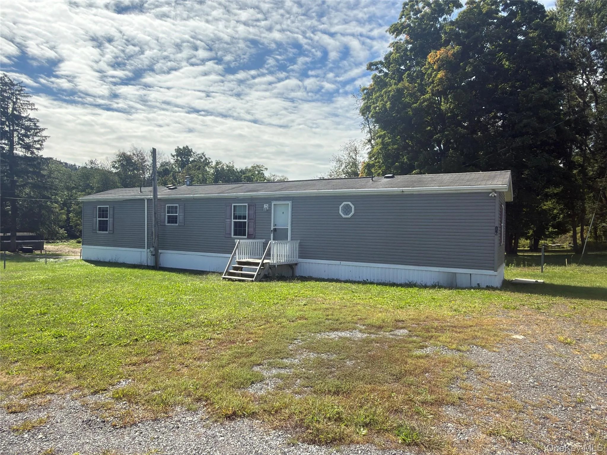 Gray siding exterior with white trim, featuring a front porch with stairs Gray siding exterior with white trim, featuring a front porch with stairs