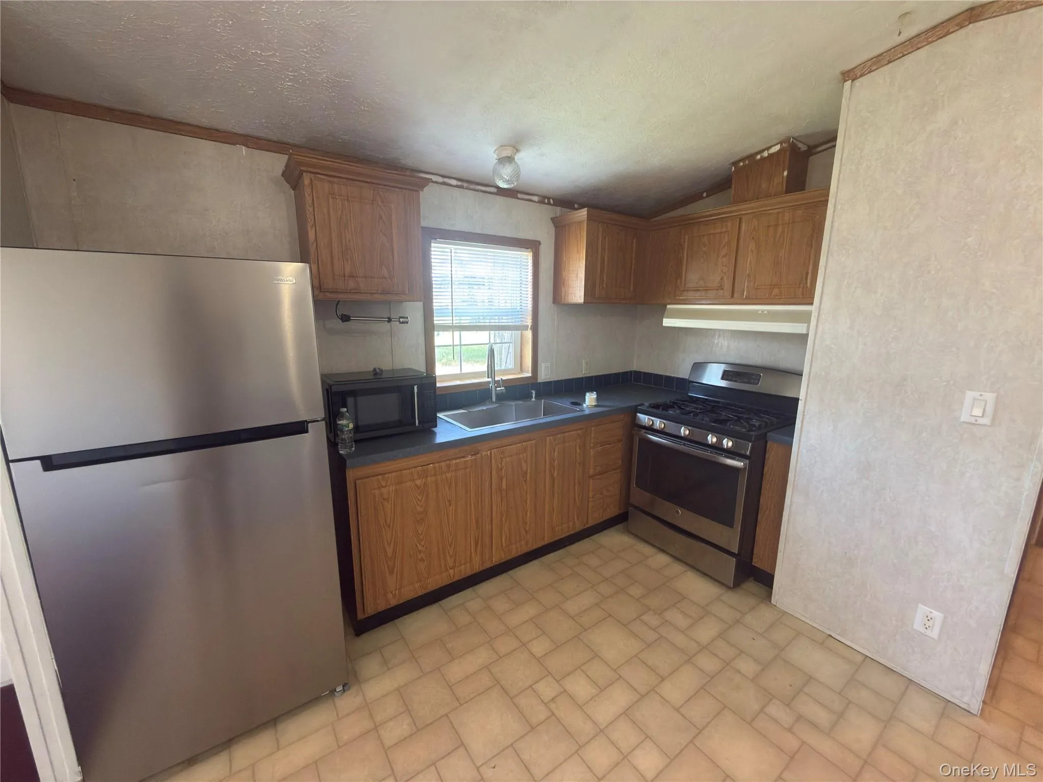 Kitchen with wood-finish cabinetry, stainless steel appliances, and a double basin sink Kitchen with wood-finish cabinetry, stainless steel appliances, and a double basin sink