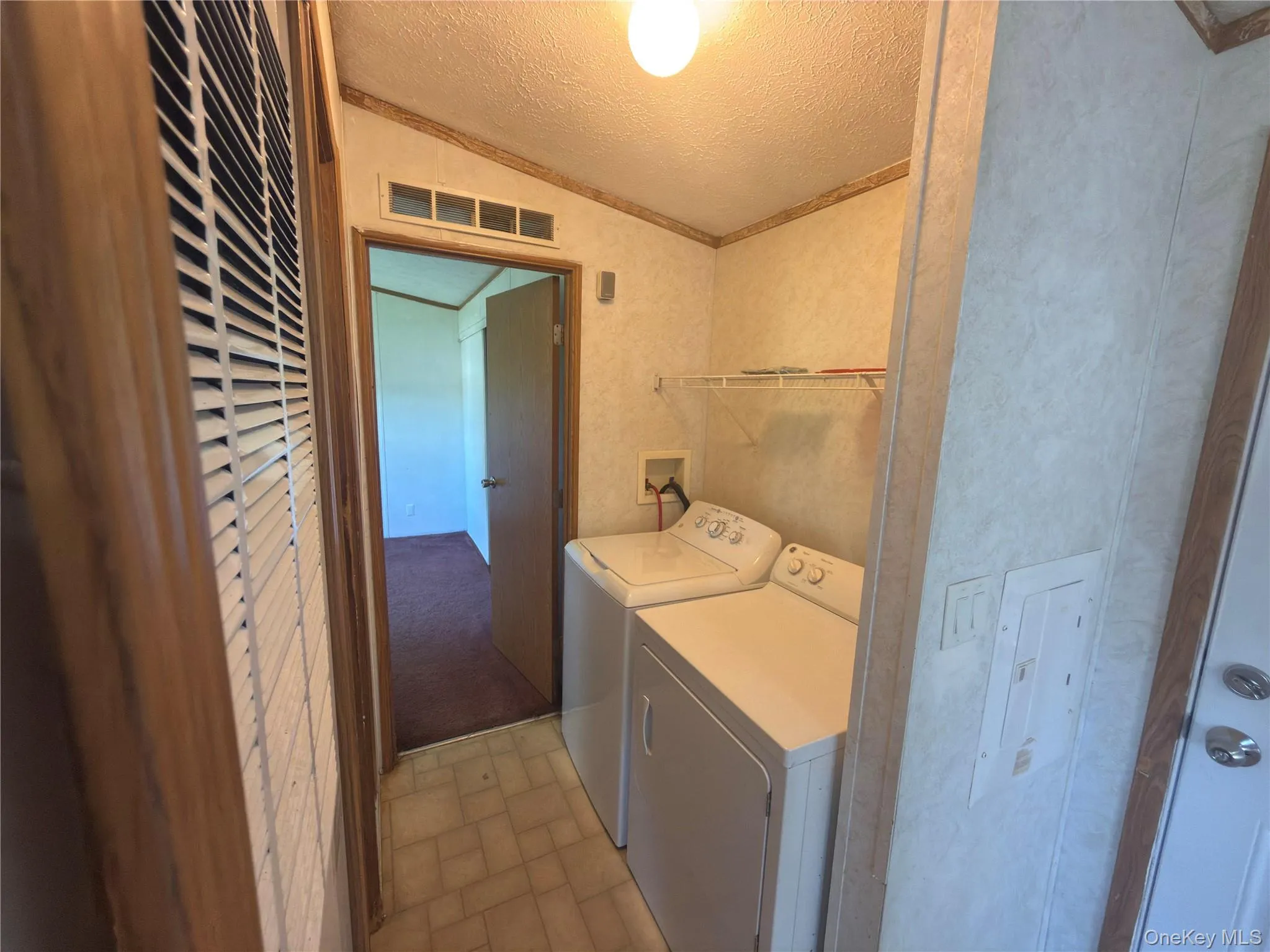 Utility area with vinyl tile flooring, white wire shelving, and overhead lighting Utility area with vinyl tile flooring, white wire shelving, and overhead lighting
