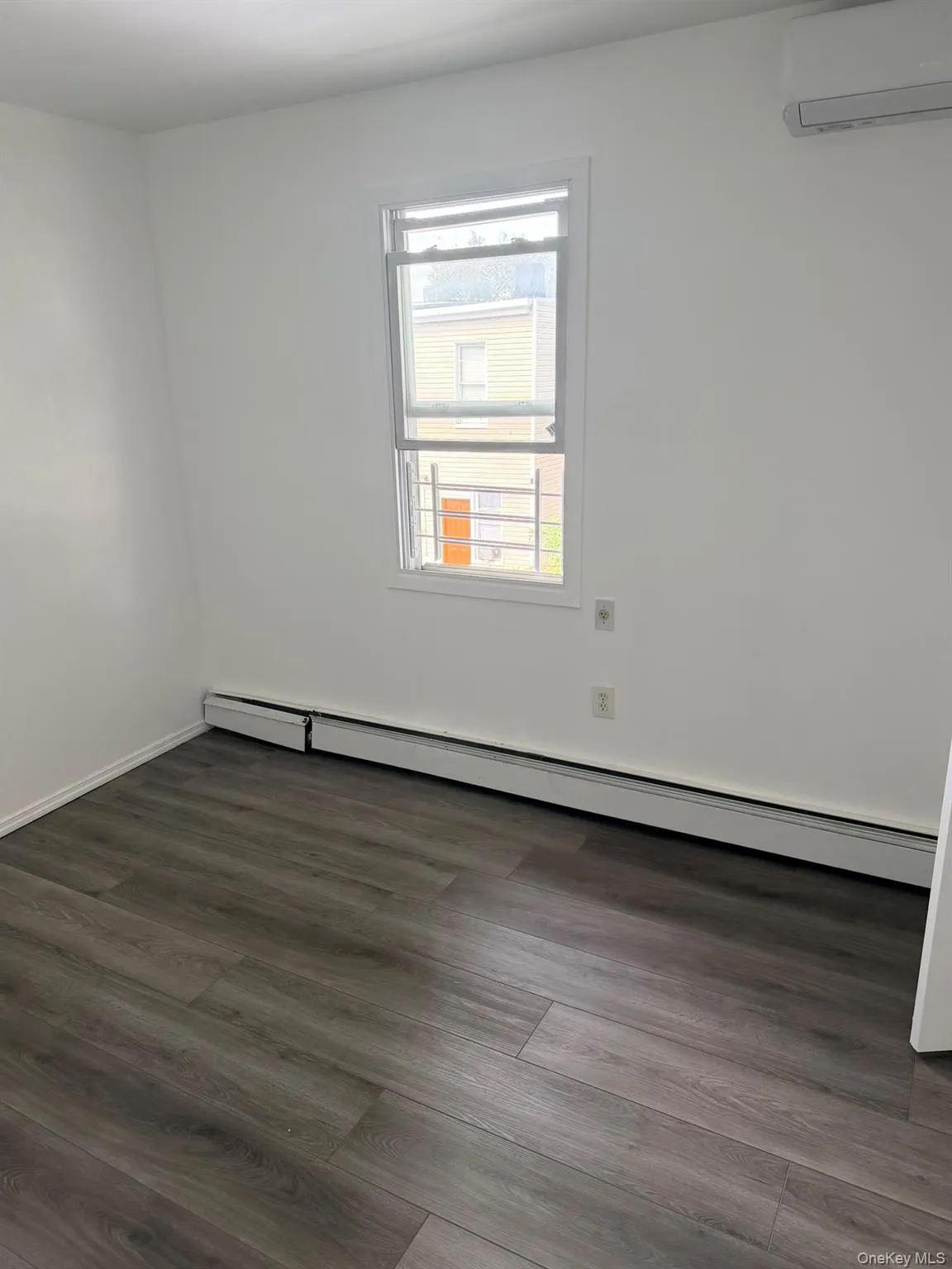 Wood-finish flooring, white painted walls, and a window with a security screen Wood-finish flooring, white painted walls, and a window with a security screen