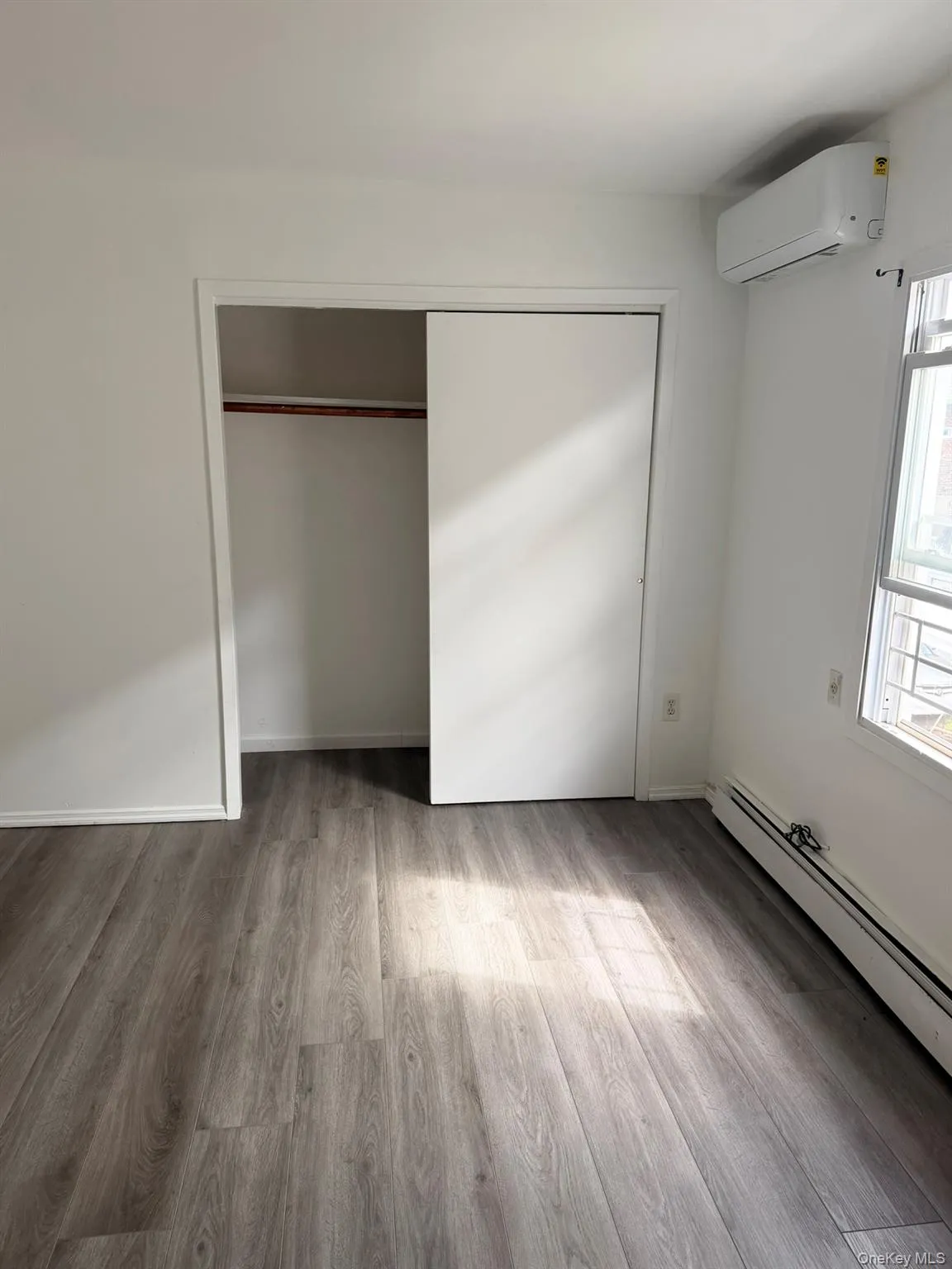 Wood-finish flooring, white walls, and a sliding closet door Wood-finish flooring, white walls, and a sliding closet door