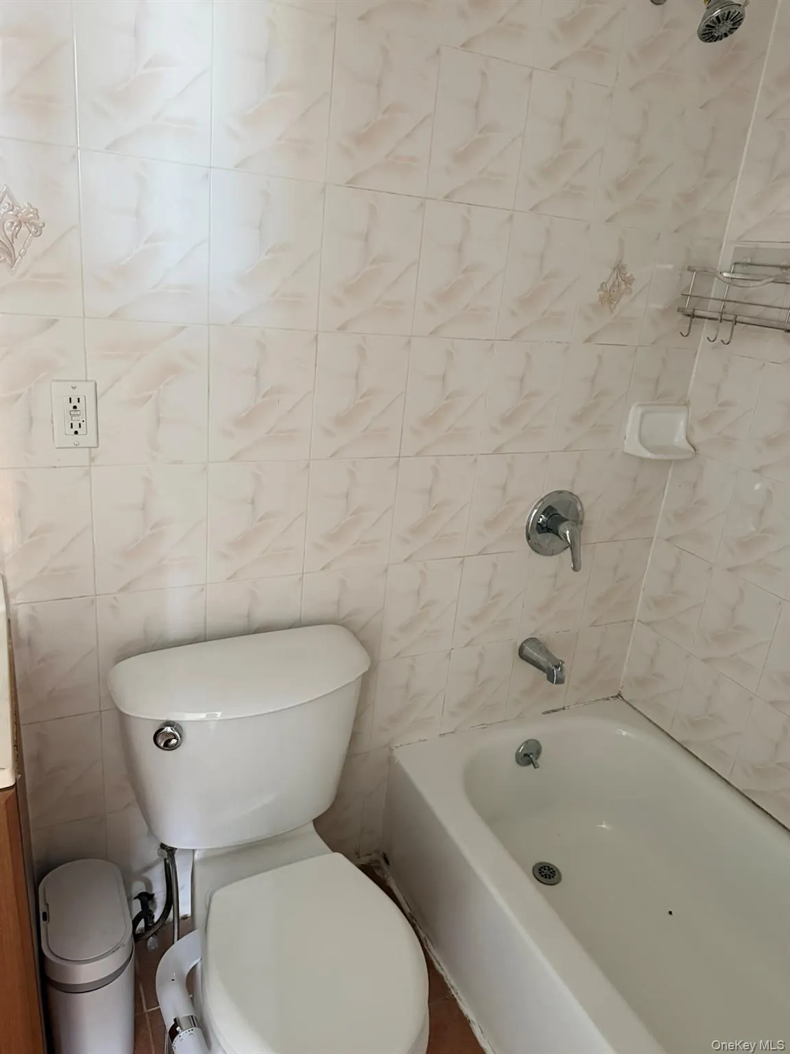 White bathtub with chrome fixtures, a white toilet, and tiled walls White bathtub with chrome fixtures, a white toilet, and tiled walls