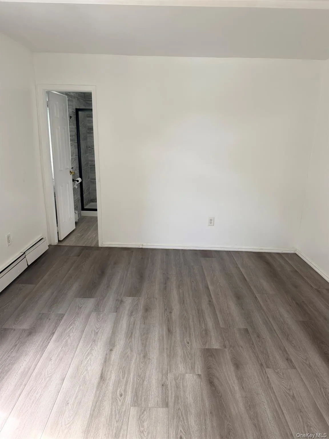Light-toned wood-finish flooring, white walls, white baseboard trim, and white door Light-toned wood-finish flooring, white walls, white baseboard trim, and white door